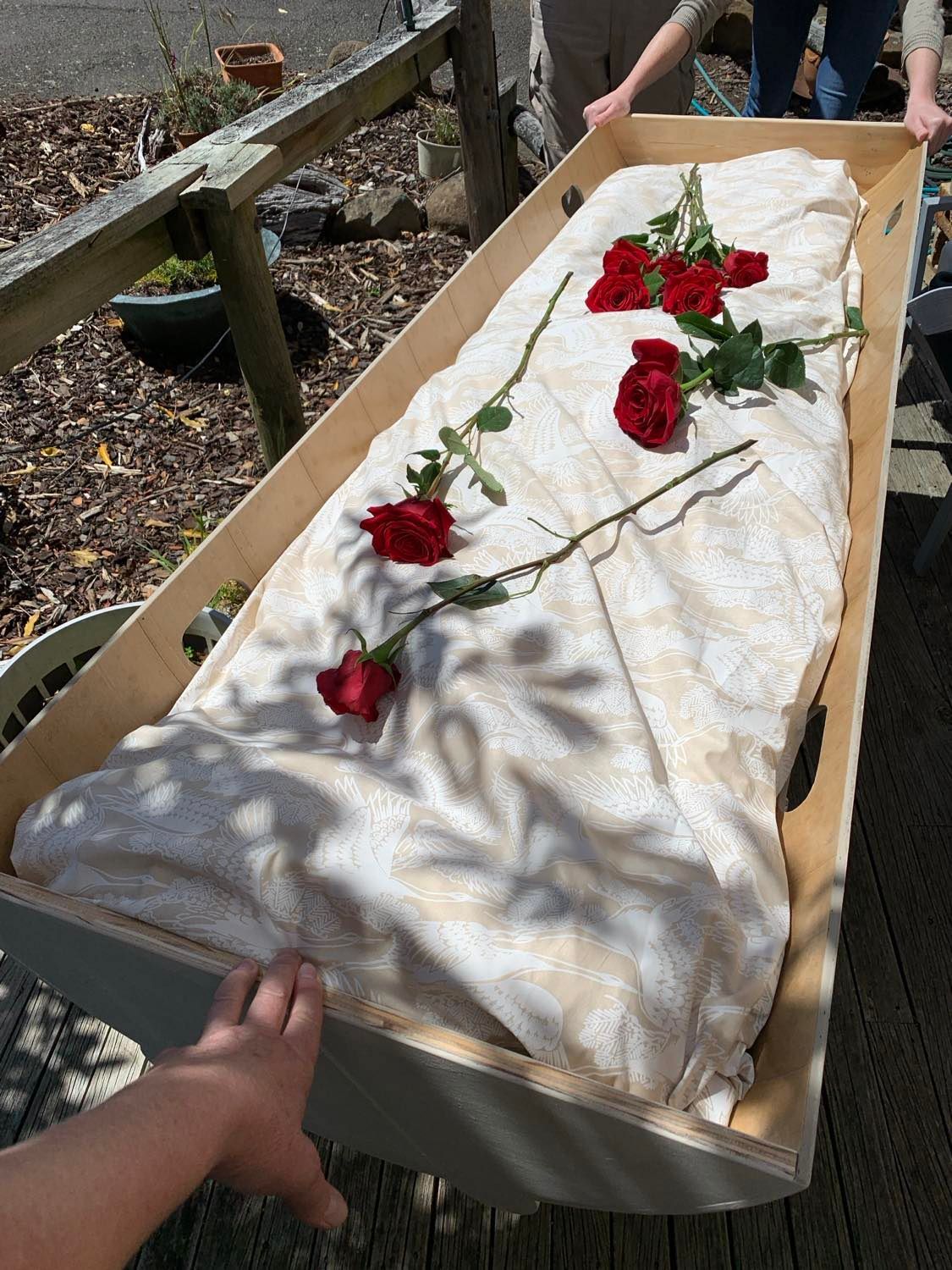 A person is holding a natural PeacePod shroud bearer with roses on it.