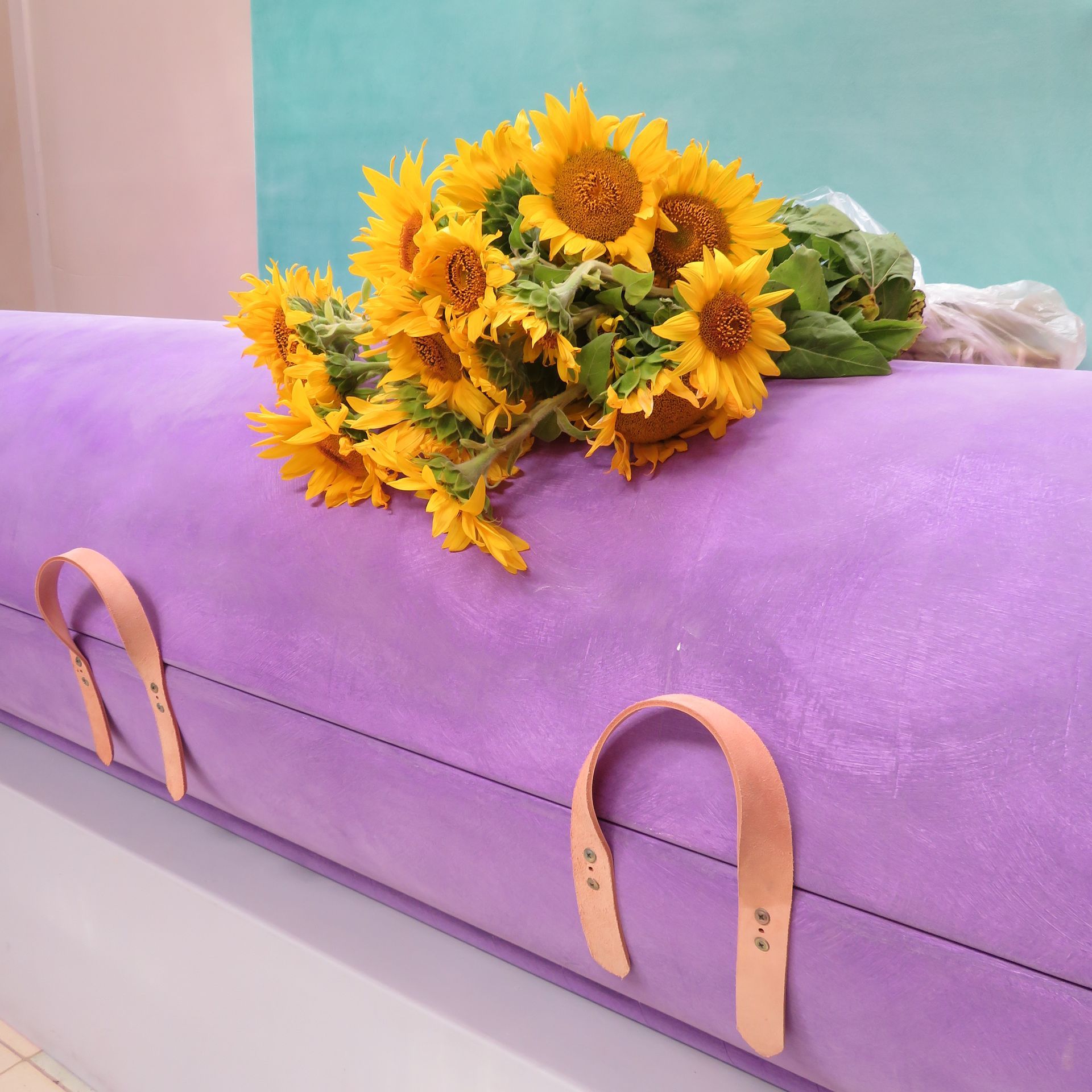 A purple coffin with sunflowers on top of it