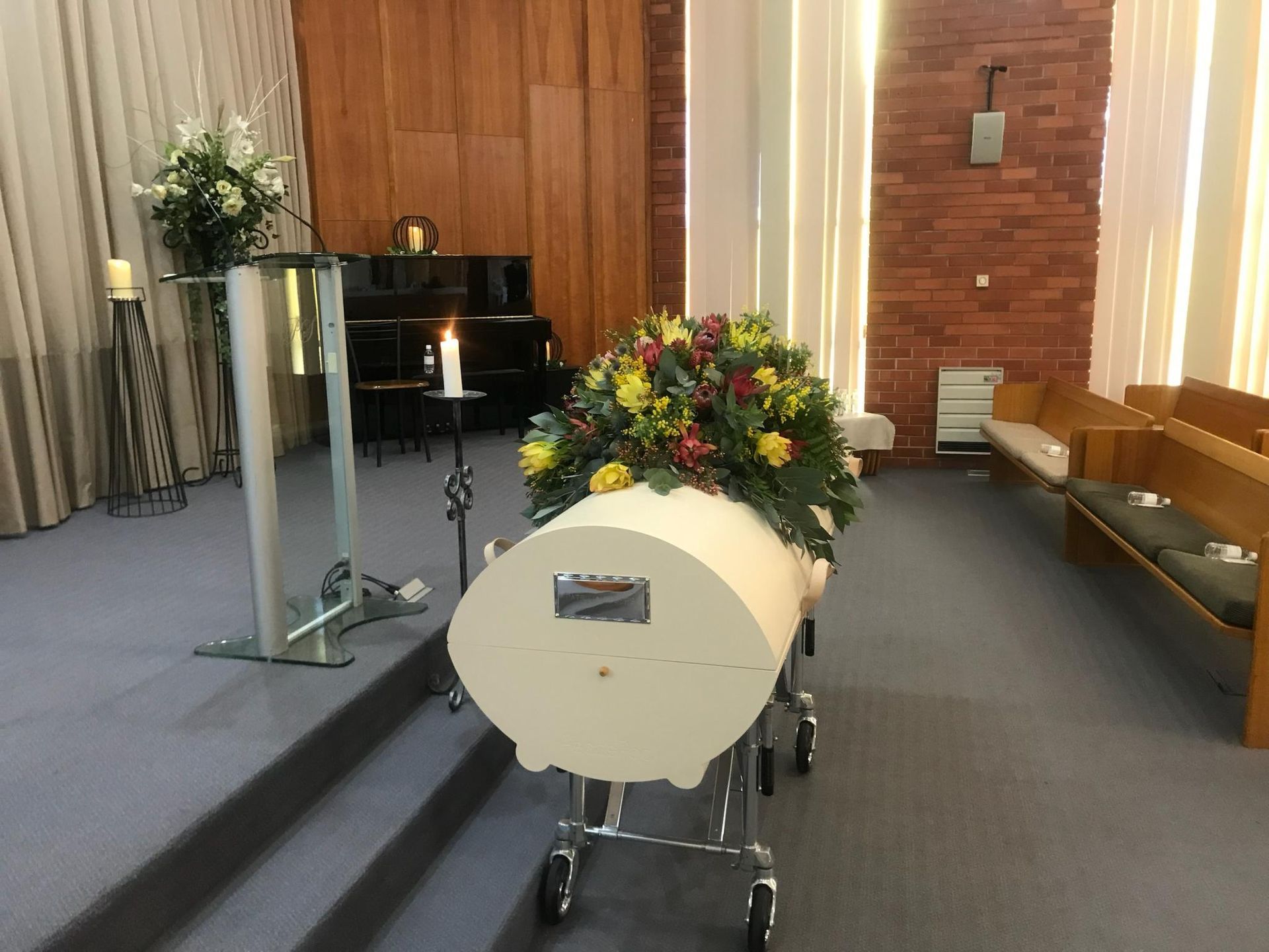 A white coffin with flowers on it is in a church.
