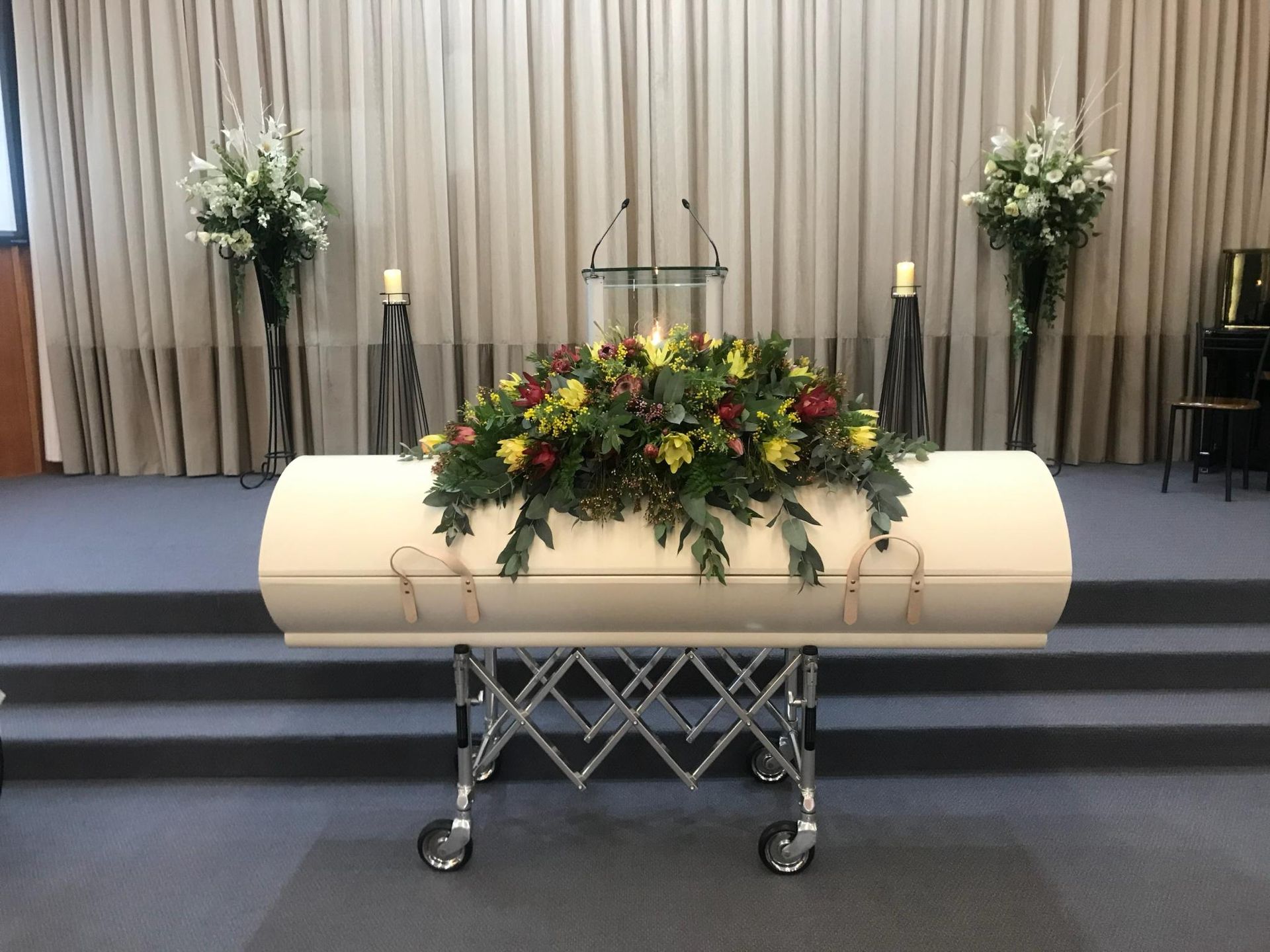 A white coffin with flowers on top of it in a church.