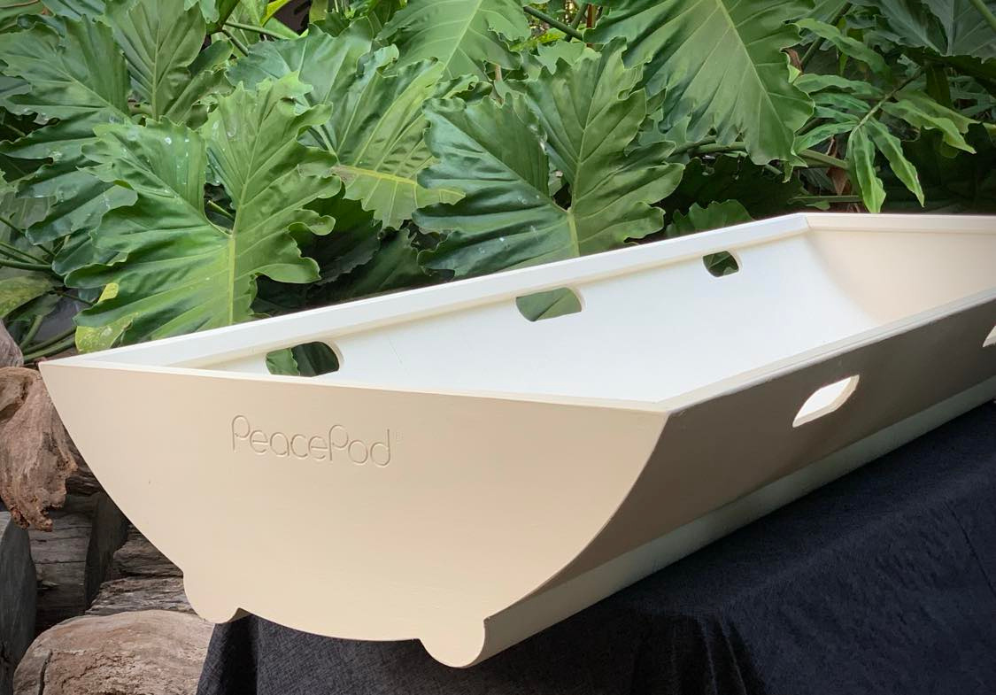 A white PeacePod shroud bearer tray is sitting on top of a black table.