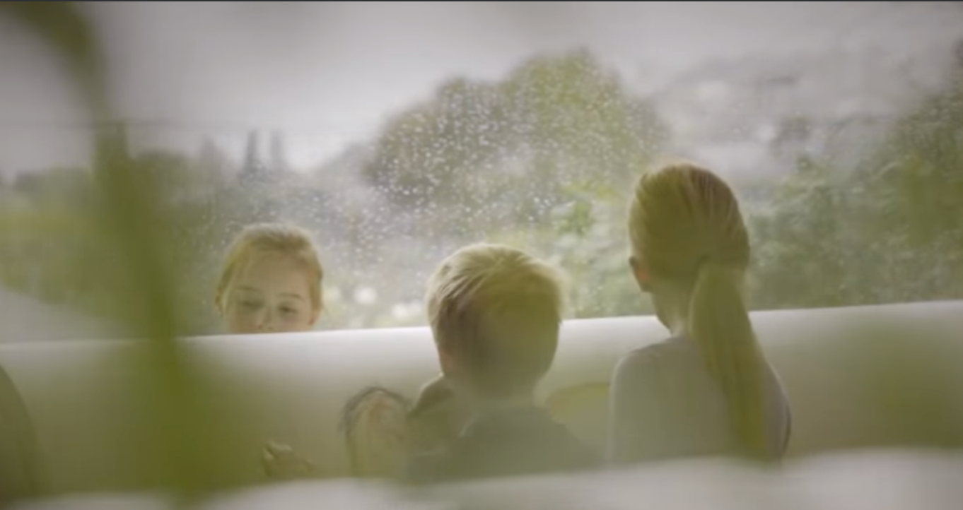 A group of children are decorating a PeacePod casket with colouring in next to a window.