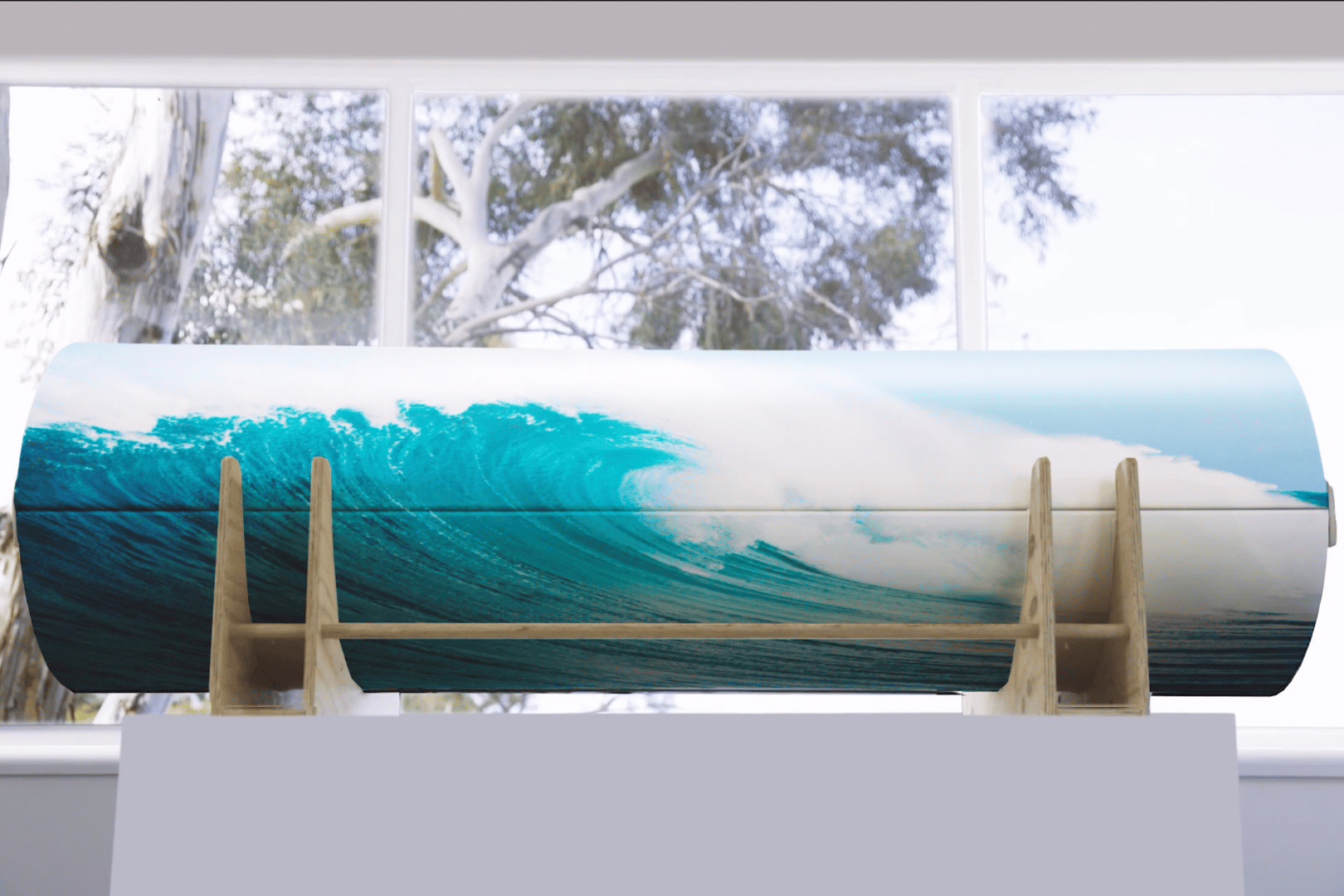 A PeacePod casket coffin with a picture of a wave on it sitting in front of a window.