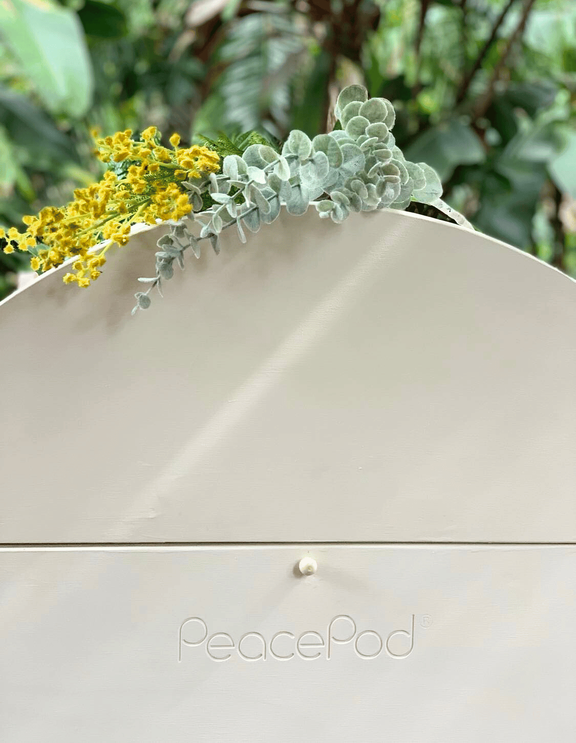 A close up of a natural PeacePod casket with flowers on top of it.