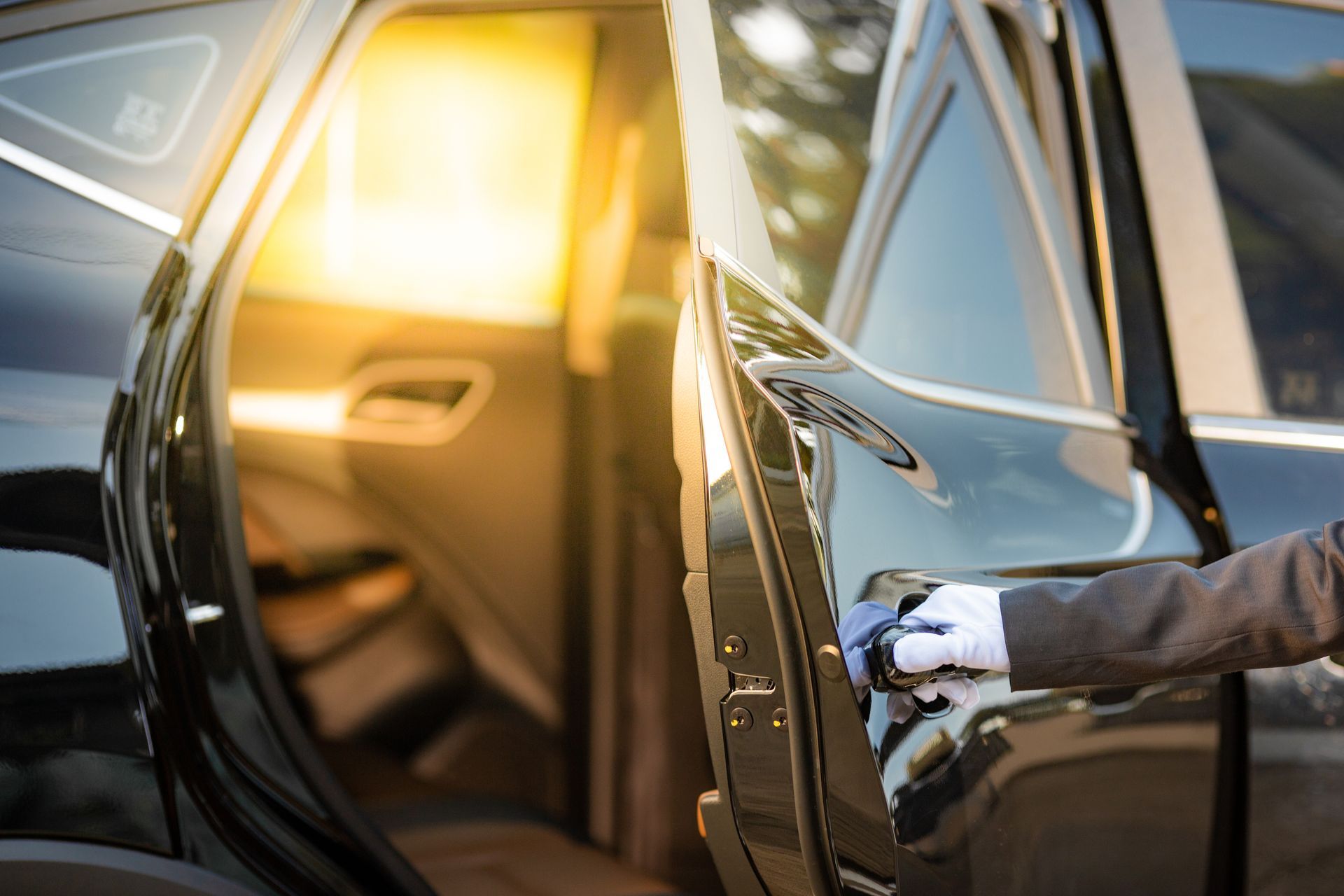 Person opening a black car door with warm sunlight inside the vehicle