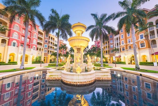 There is a fountain in the middle of a pool in front of a building.