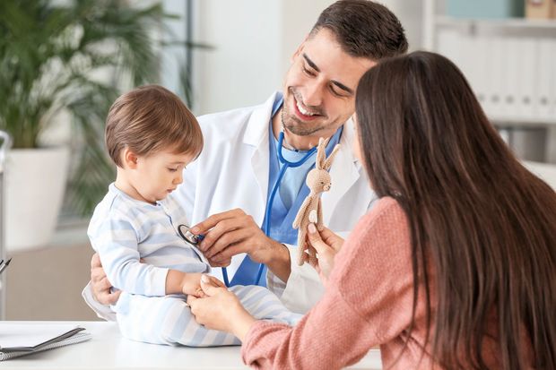 Un médico examina a un niño pequeño mientras uno de sus padres observa en una clínica.