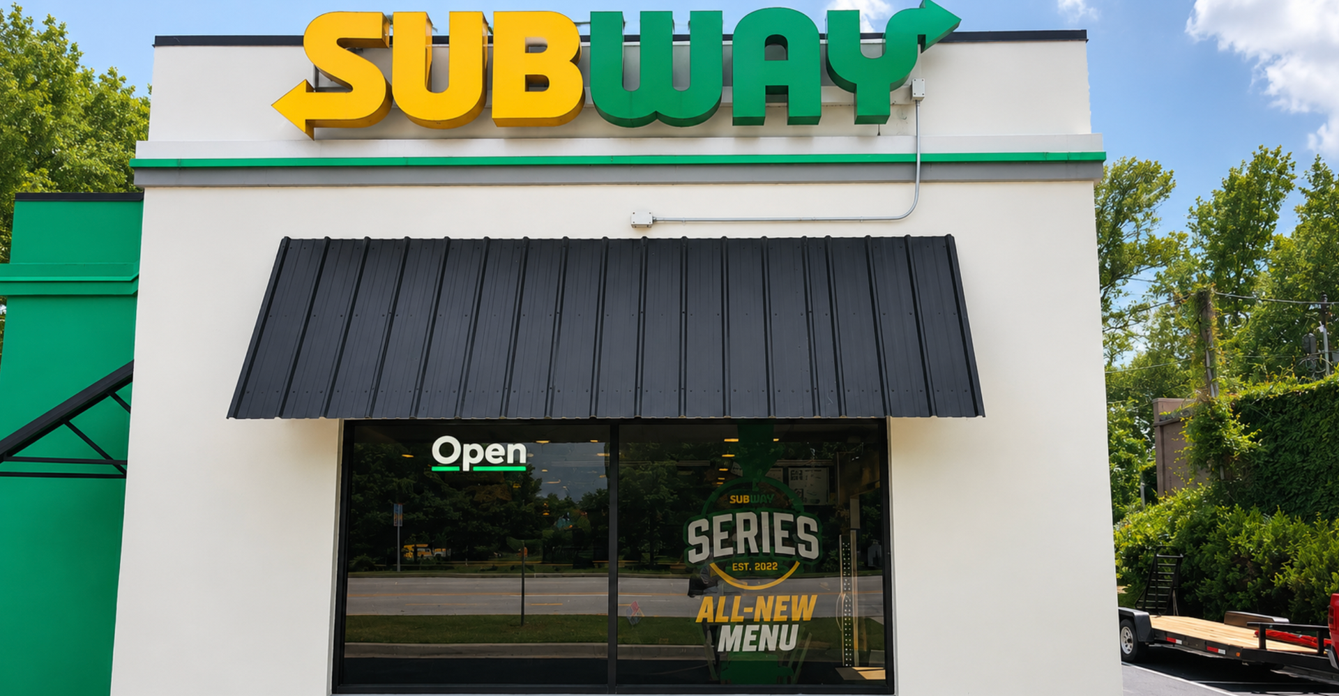 Subway restaurant storefront with yellow-green sign and black awning,