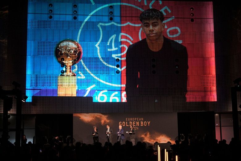 Cerimonia di premiazione del Golden Boy: un trofeo e un ragazzo vengono mostrati su uno schermo; i presentatori parlano su un palco.