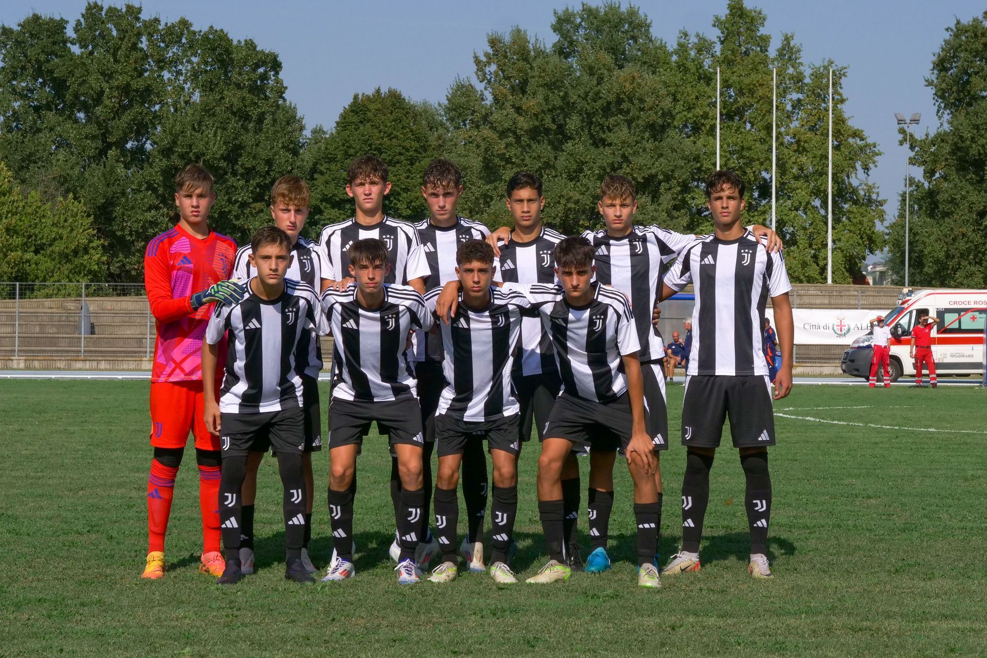 Squadra di calcio con maglie a strisce bianche e nere, in posa su un campo verde.