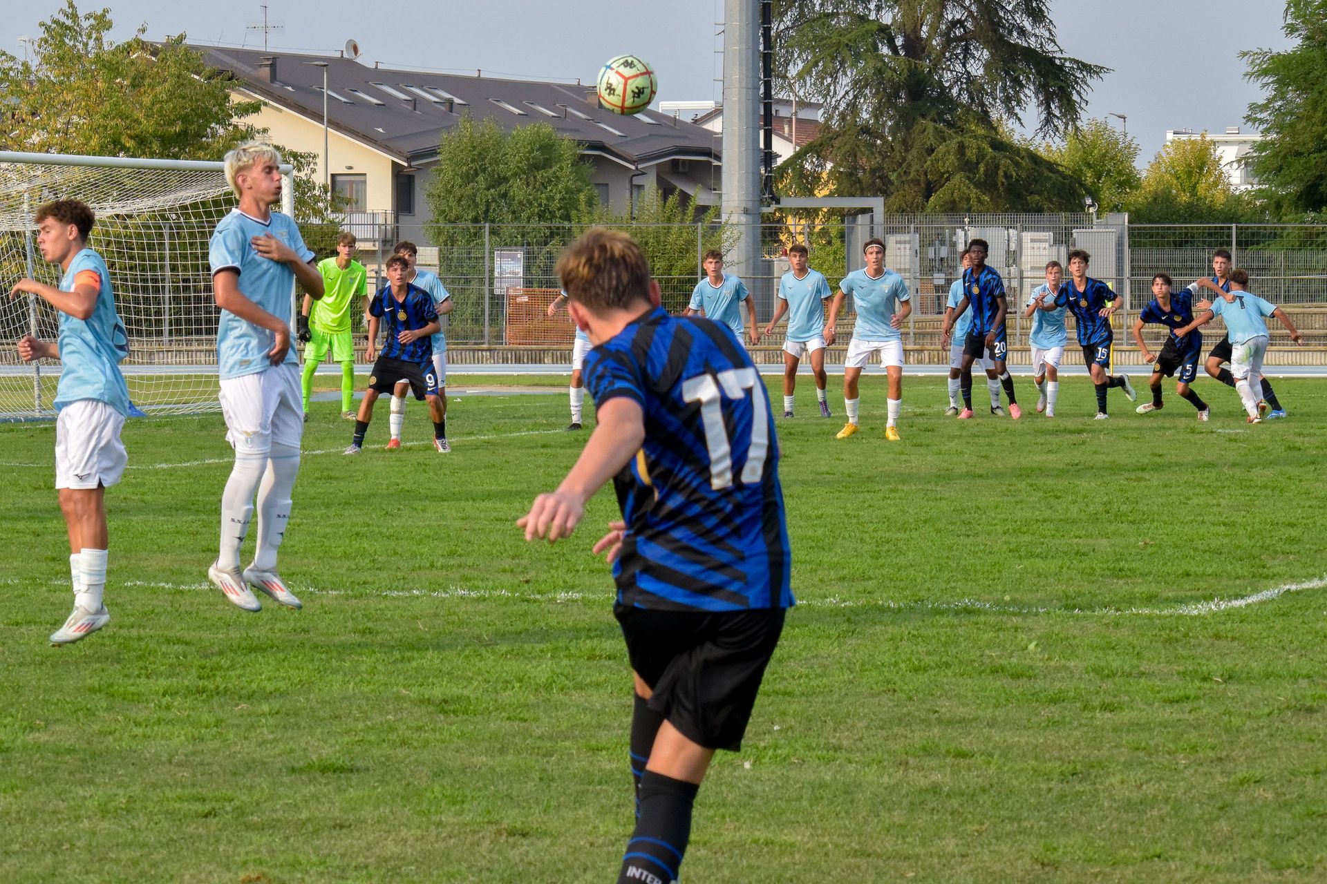 Calciatori durante un calcio di punizione: uno calcia, gli altri sono contro un muro, su un campo verde.