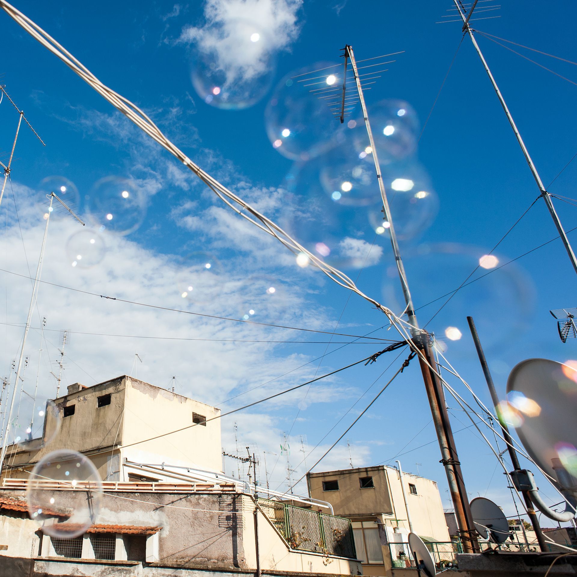 Le bolle fluttuano sui tetti con le antenne sullo sfondo di un cielo azzurro brillante.