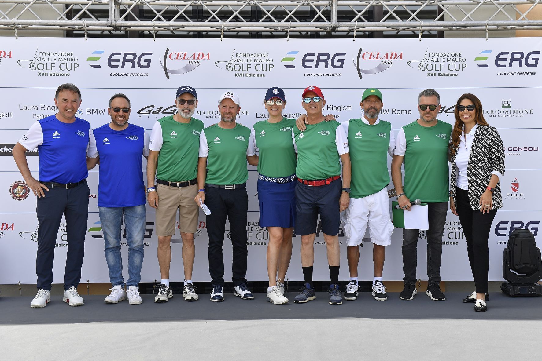 Gruppo di persone in abbigliamento sportivo in posa su un palco con striscioni degli sponsor.