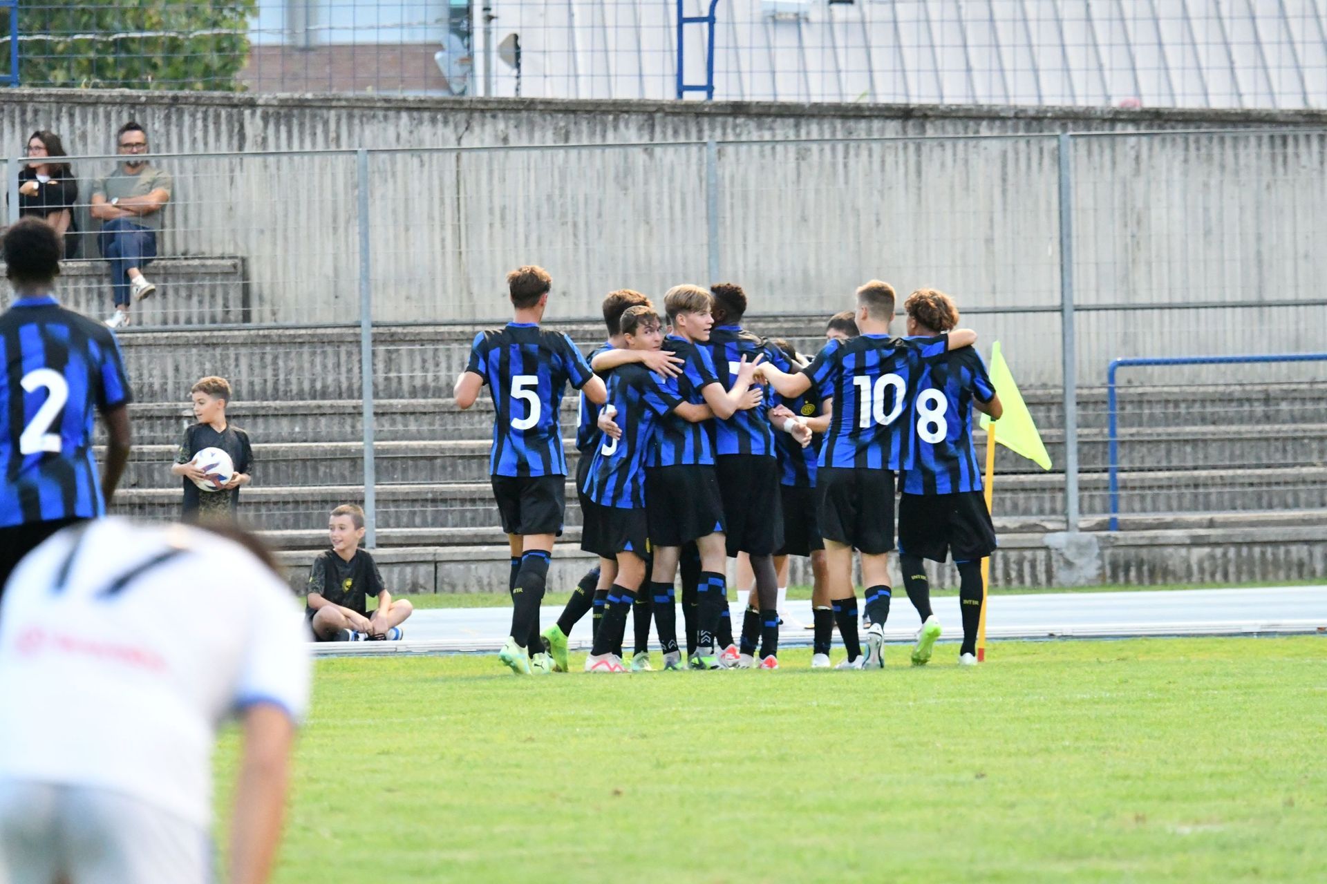 La squadra di calcio con le maglie nere e blu si stringe sul campo dopo un goal.