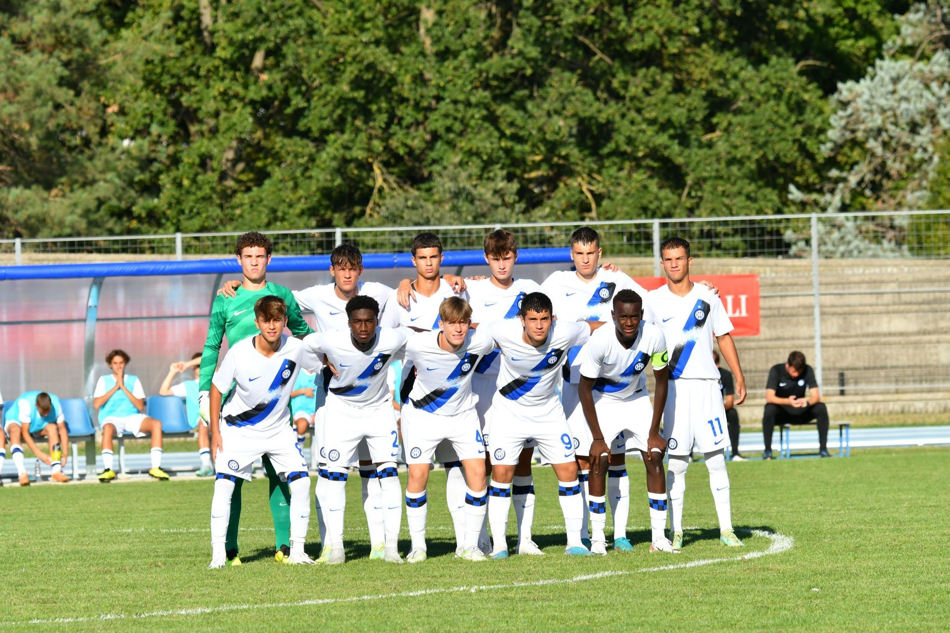 Squadra di calcio in uniforme bianca e blu in posa su un campo verde.