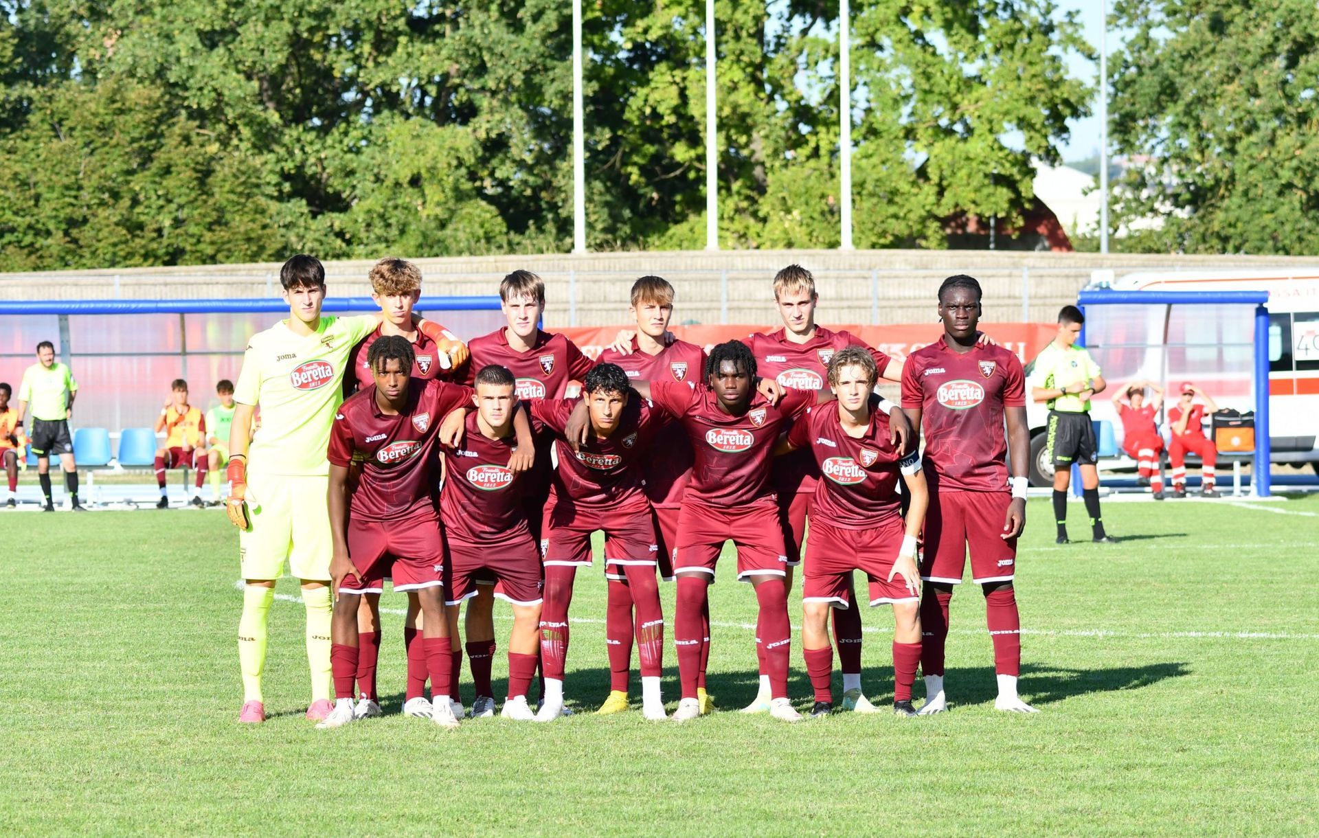 Squadra di calcio in divisa color marrone su un campo verde, in posa per una foto.