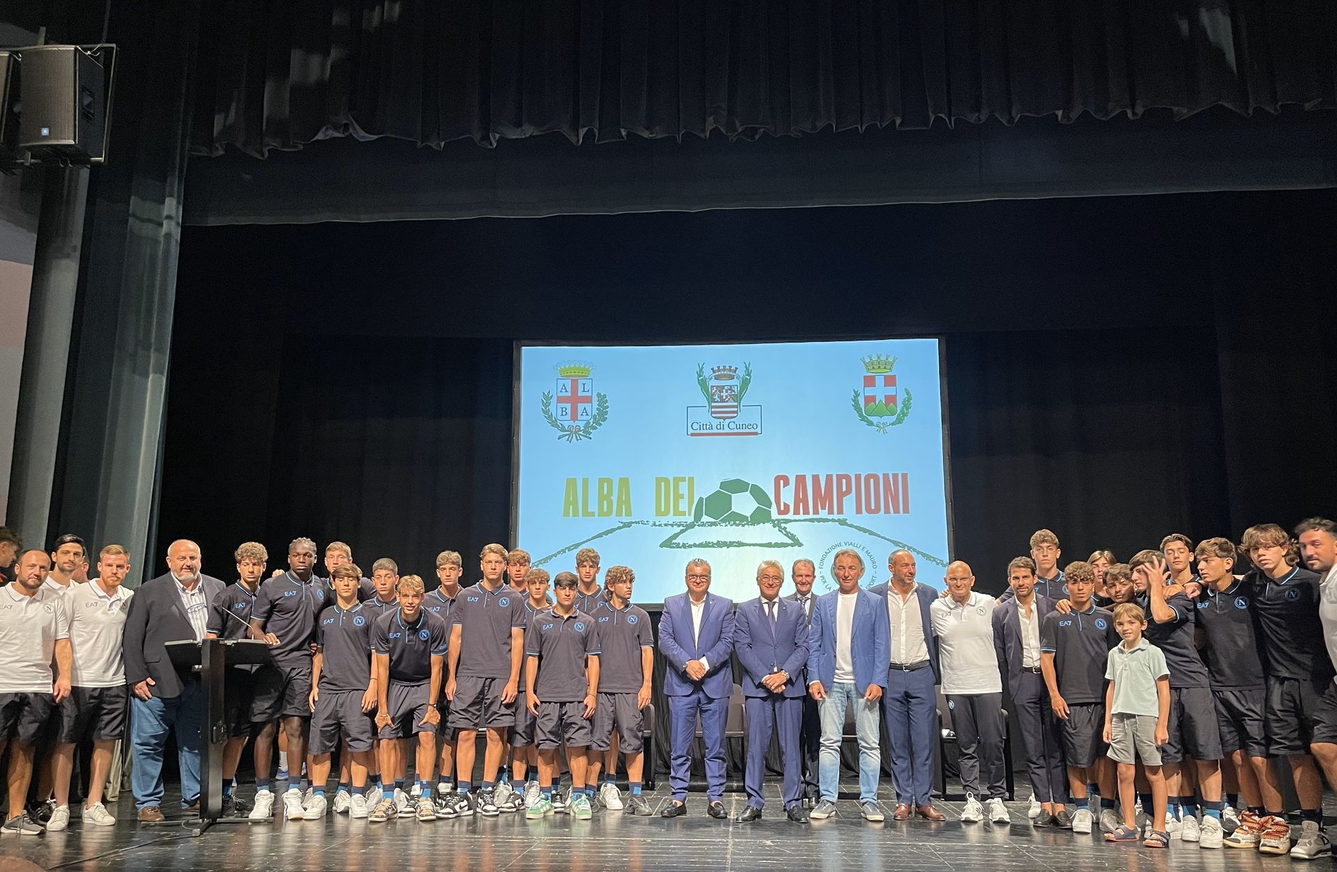 Gruppo di persone sul palco con uno striscione con la scritta