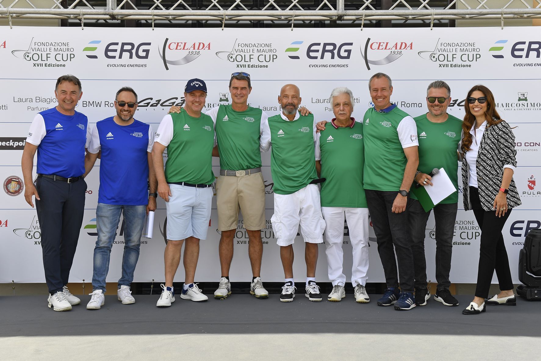Un gruppo di persone con magliette verdi posa su un palco per un evento di golf.