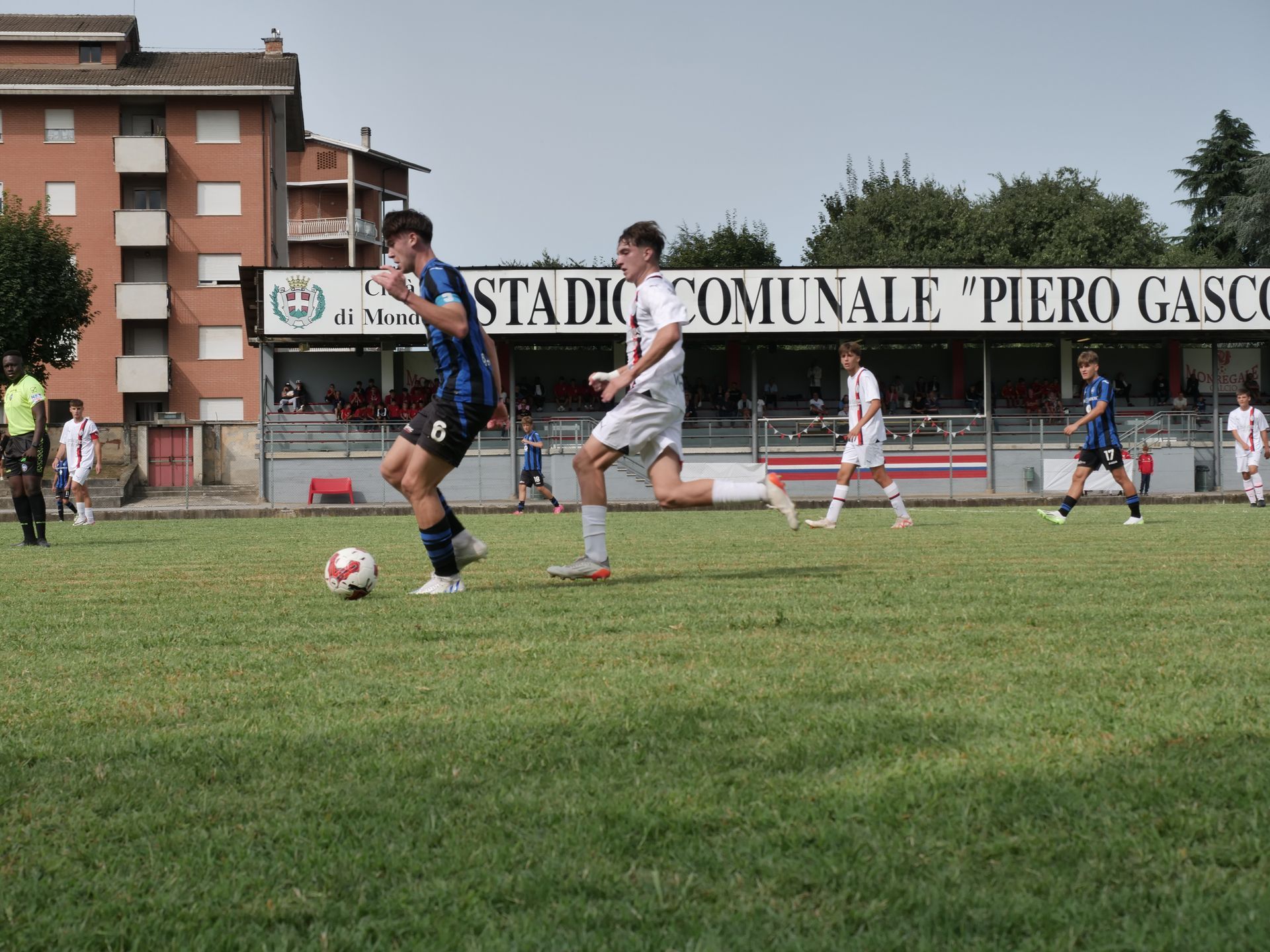 Giocatori di calcio su un campo verde in uno stadio. Un giocatore palleggia verso un altro giocatore.
