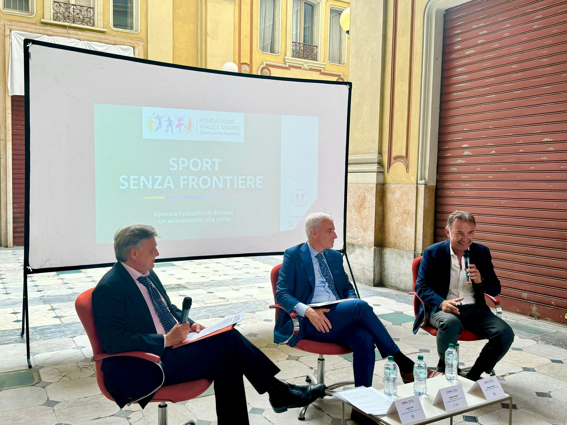Tre uomini seduti, mentre parlano, a un evento