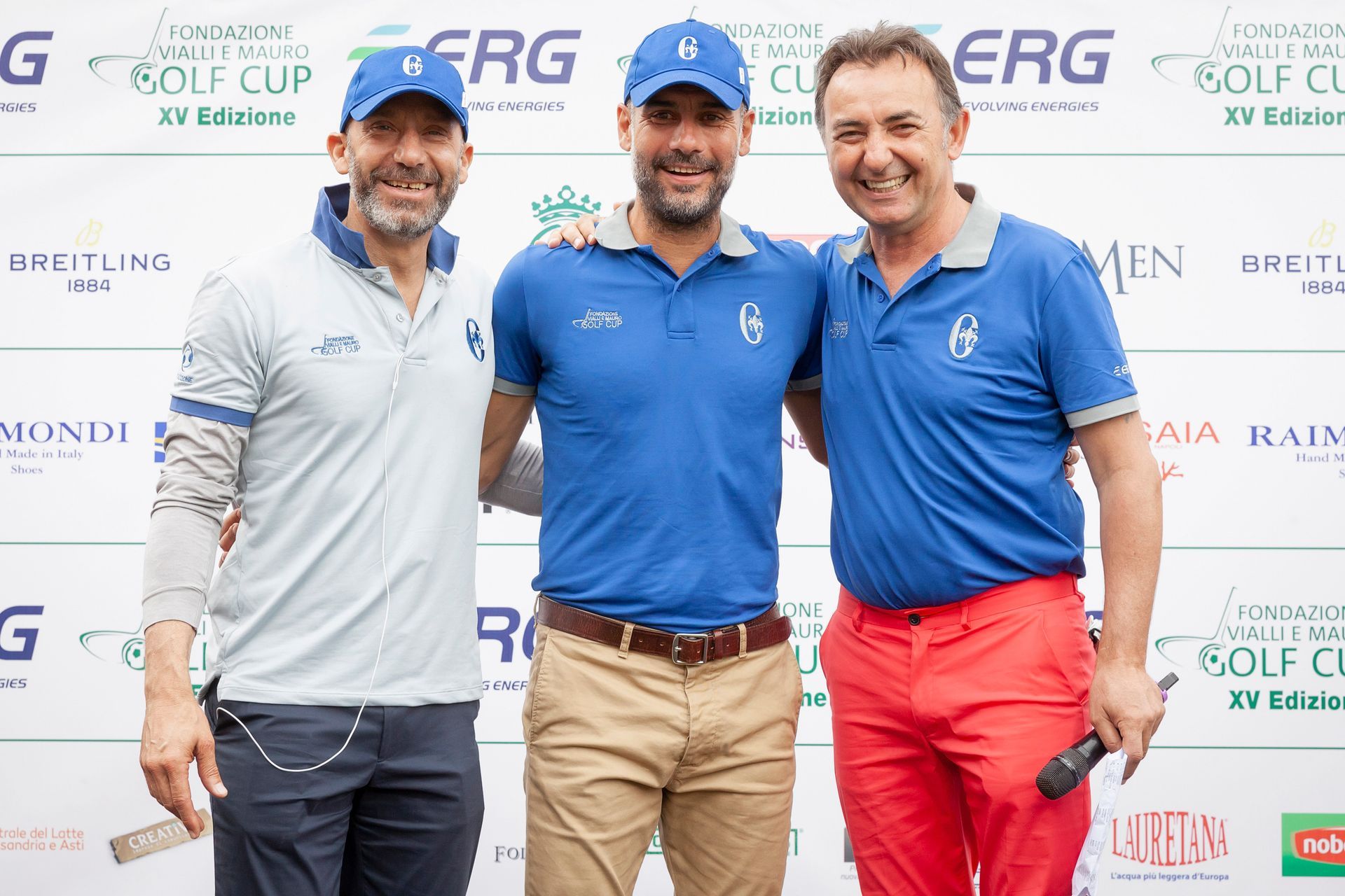 Tre uomini in tenuta da golf posano insieme all'aperto, sorridenti. Due indossano pantaloni blu, uno pantaloni rossi; tutti e tre hanno il cappello.