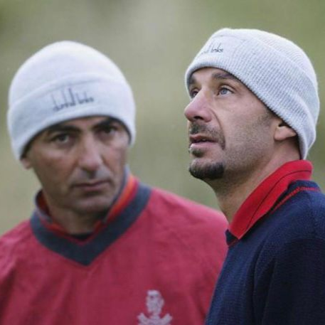 Due uomini in giacca e cravatta tengono in mano dei microfoni su un palco e parlano. Sullo sfondo ci sono i loghi aziendali.