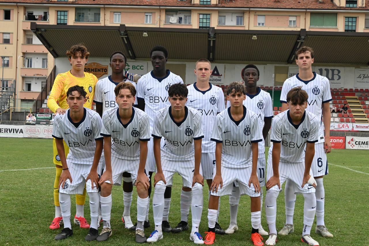 Giocatori di calcio in divisa blu e nera festeggiano un gol su un campo verde.