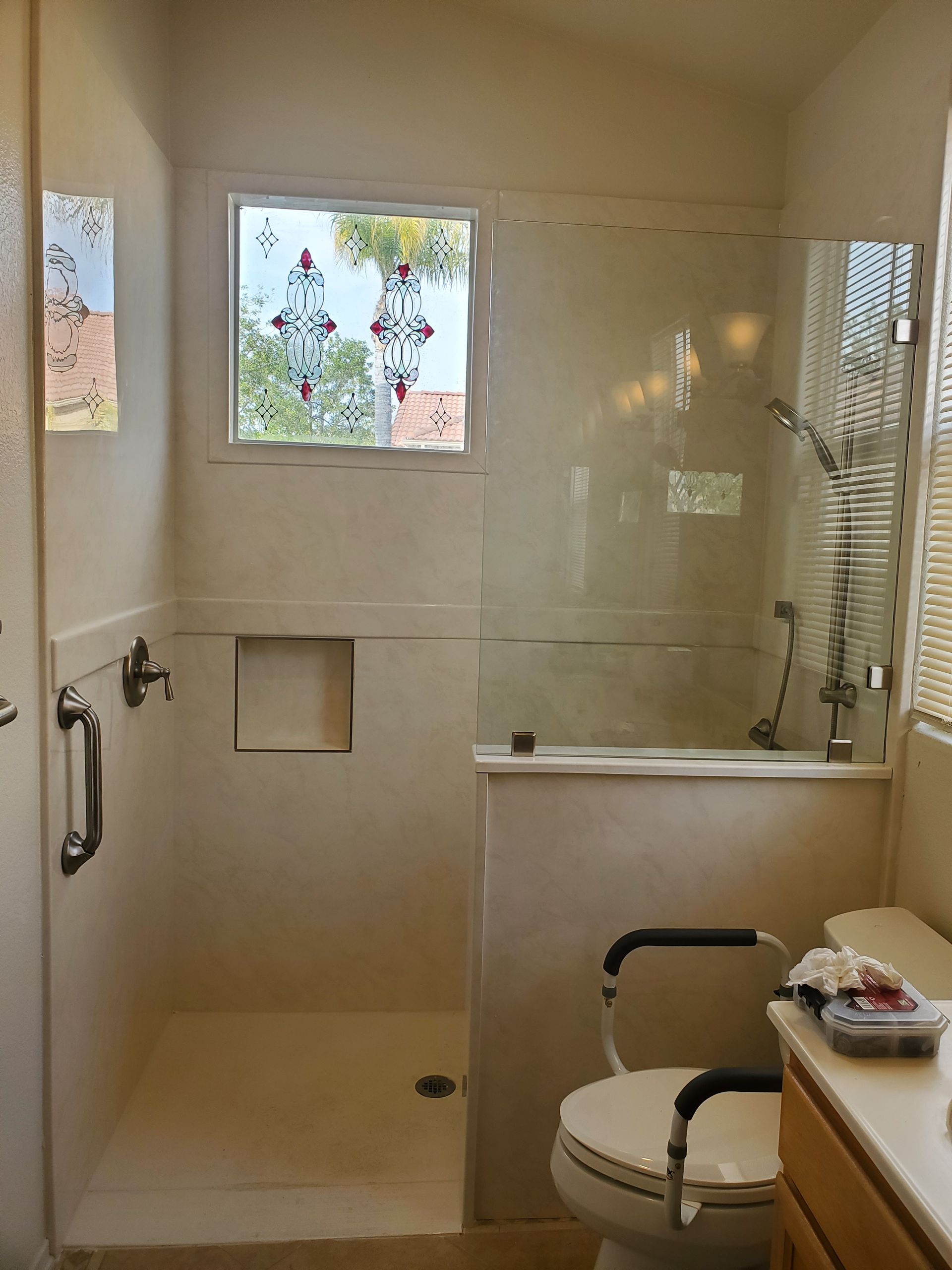 Accessible bathroom featuring a walk-in shower with a grab bar and a toilet equipped with safety rails.