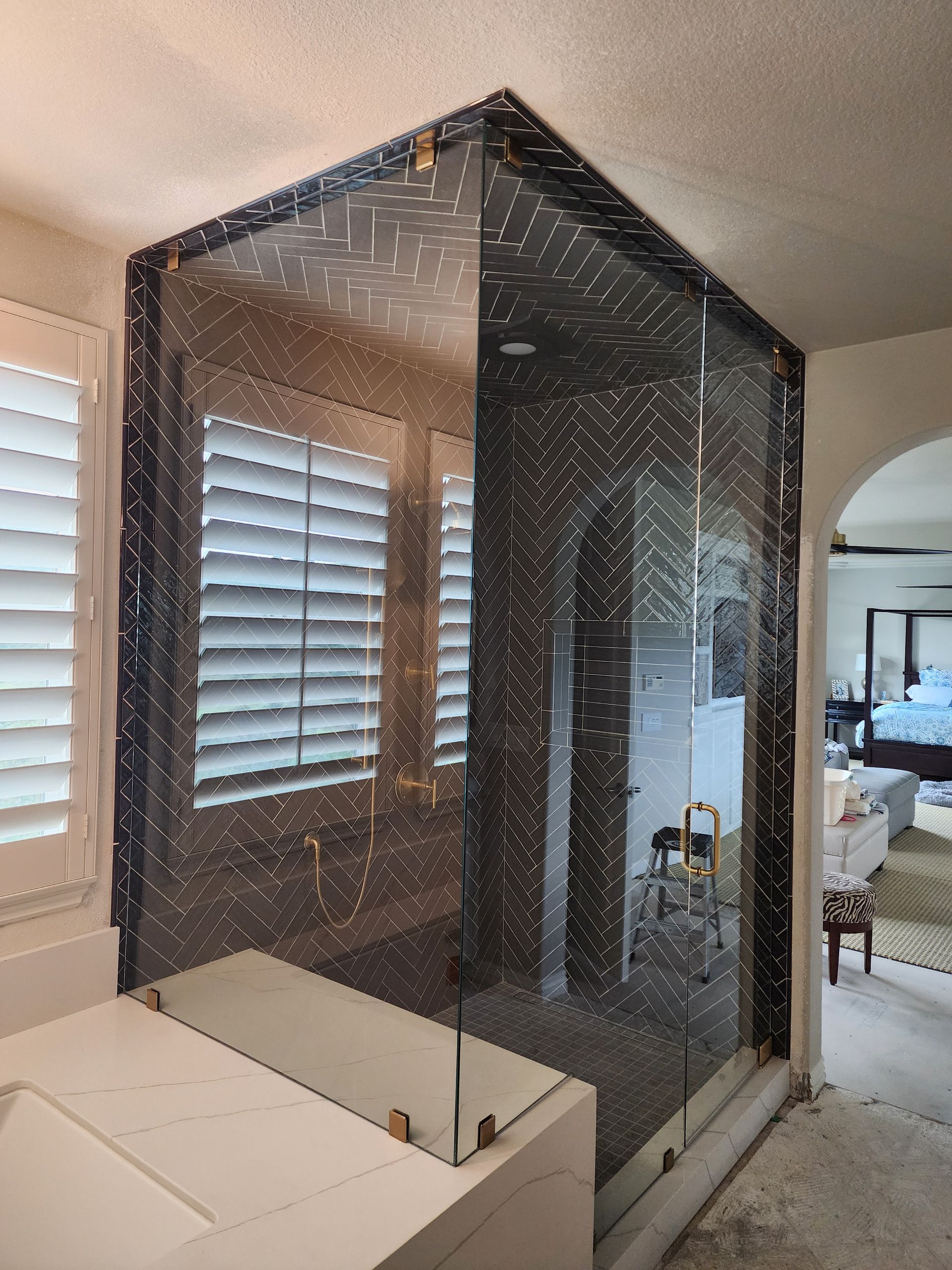 A shower enclosure with protective black masking film partially covering the glass panels in a bathroom.