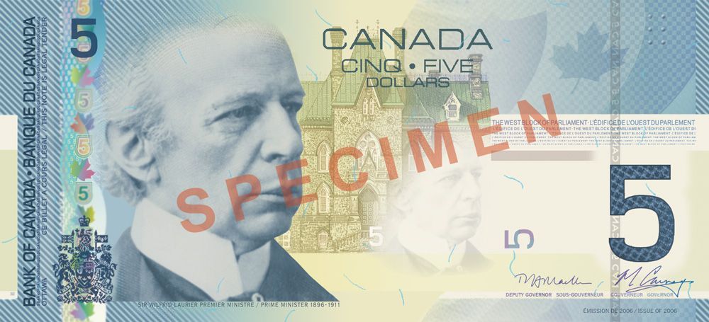 A canadian five dollar bill with a picture of a man on it.