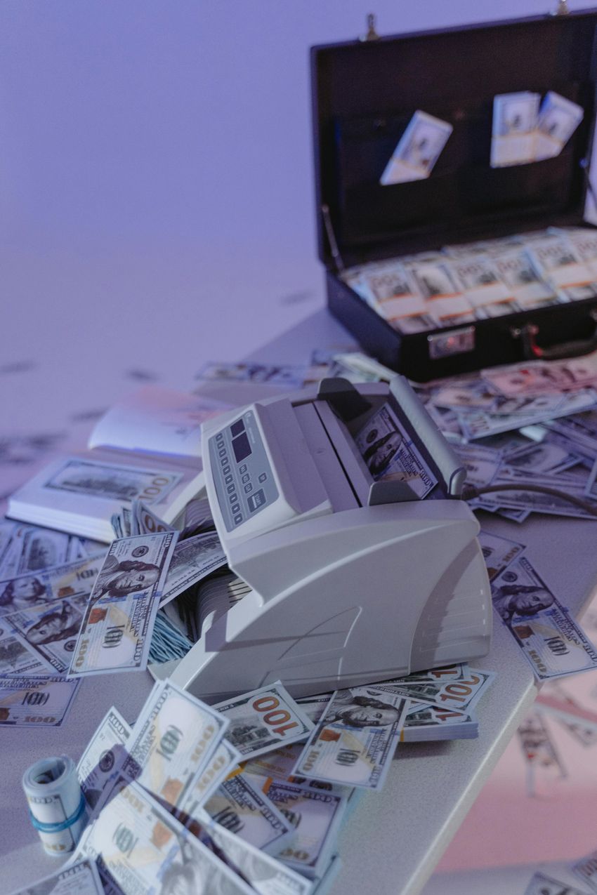 A machine is sitting on top of a pile of money on a table.
