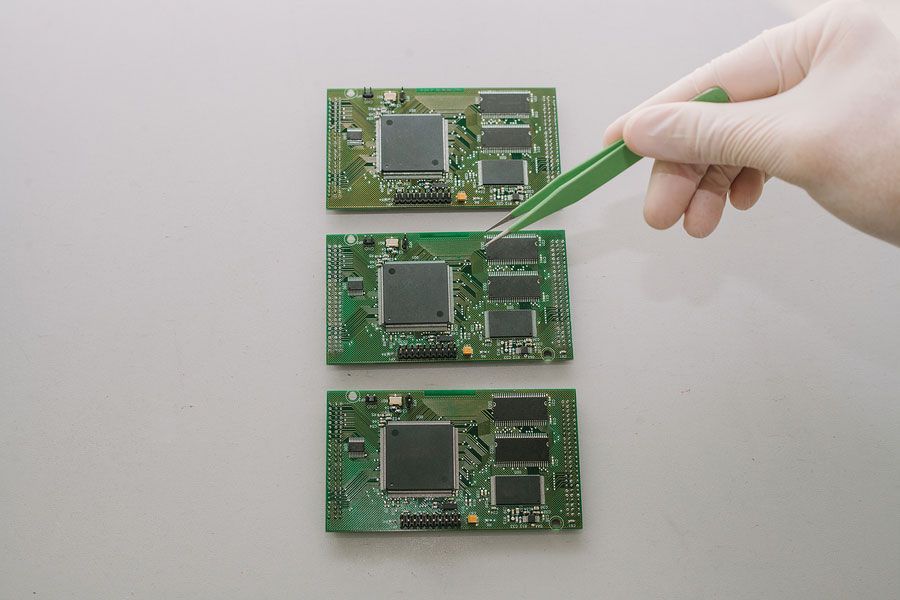 A person is working on a motherboard with tweezers.