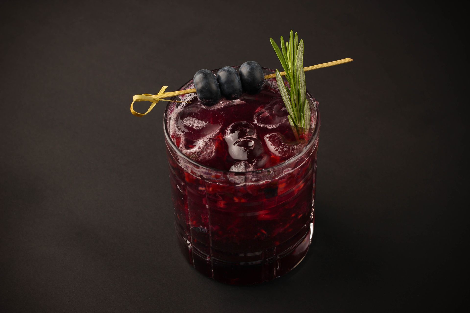 Sushi Restaurant | Finding Sushi | Dark red cocktail in a glass with ice, lemon peel, blueberries, and rosemary garnish