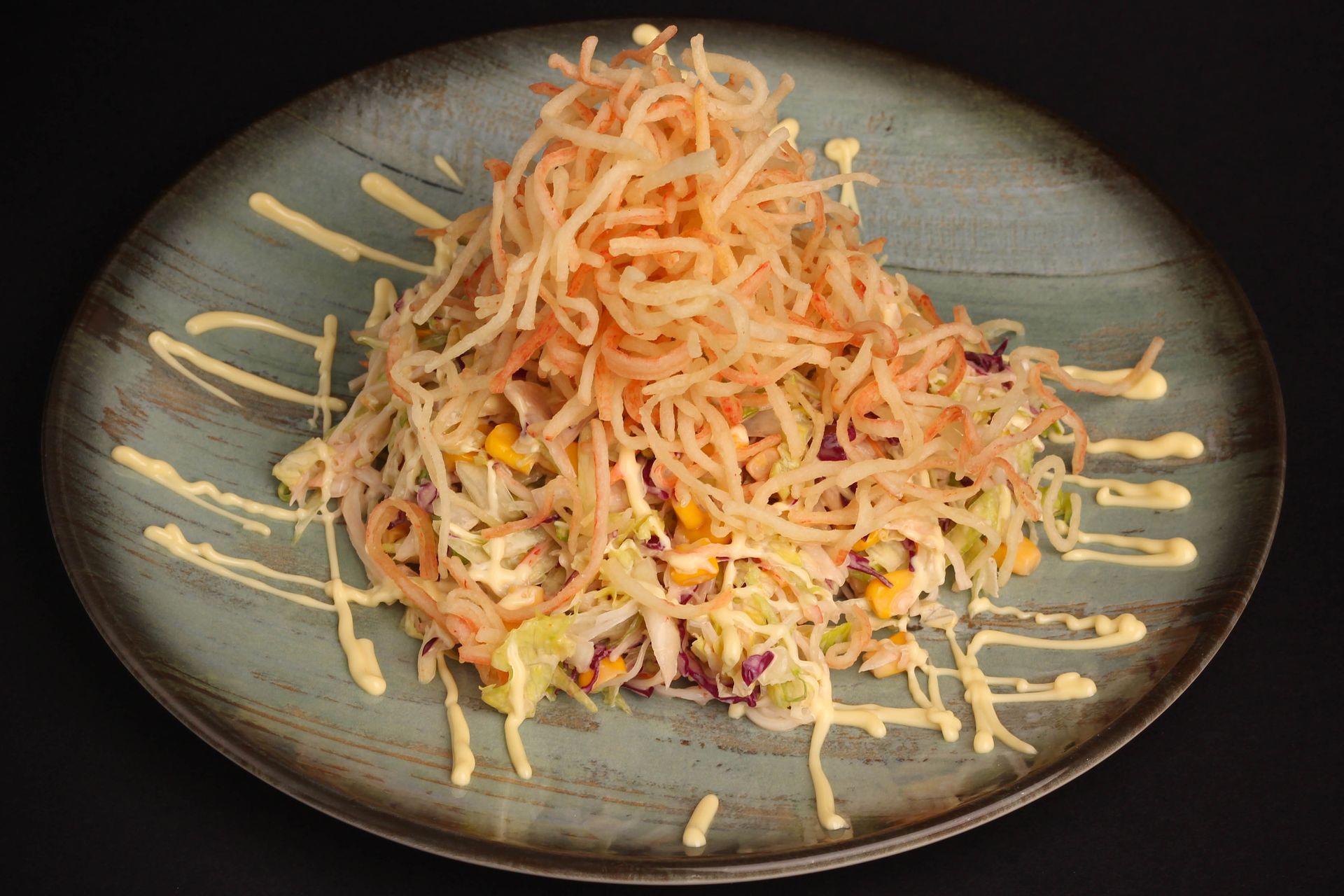 Sushi Restaurant | Finding Sushi | Shredded salad topped with carrots and dressing on a dark plate