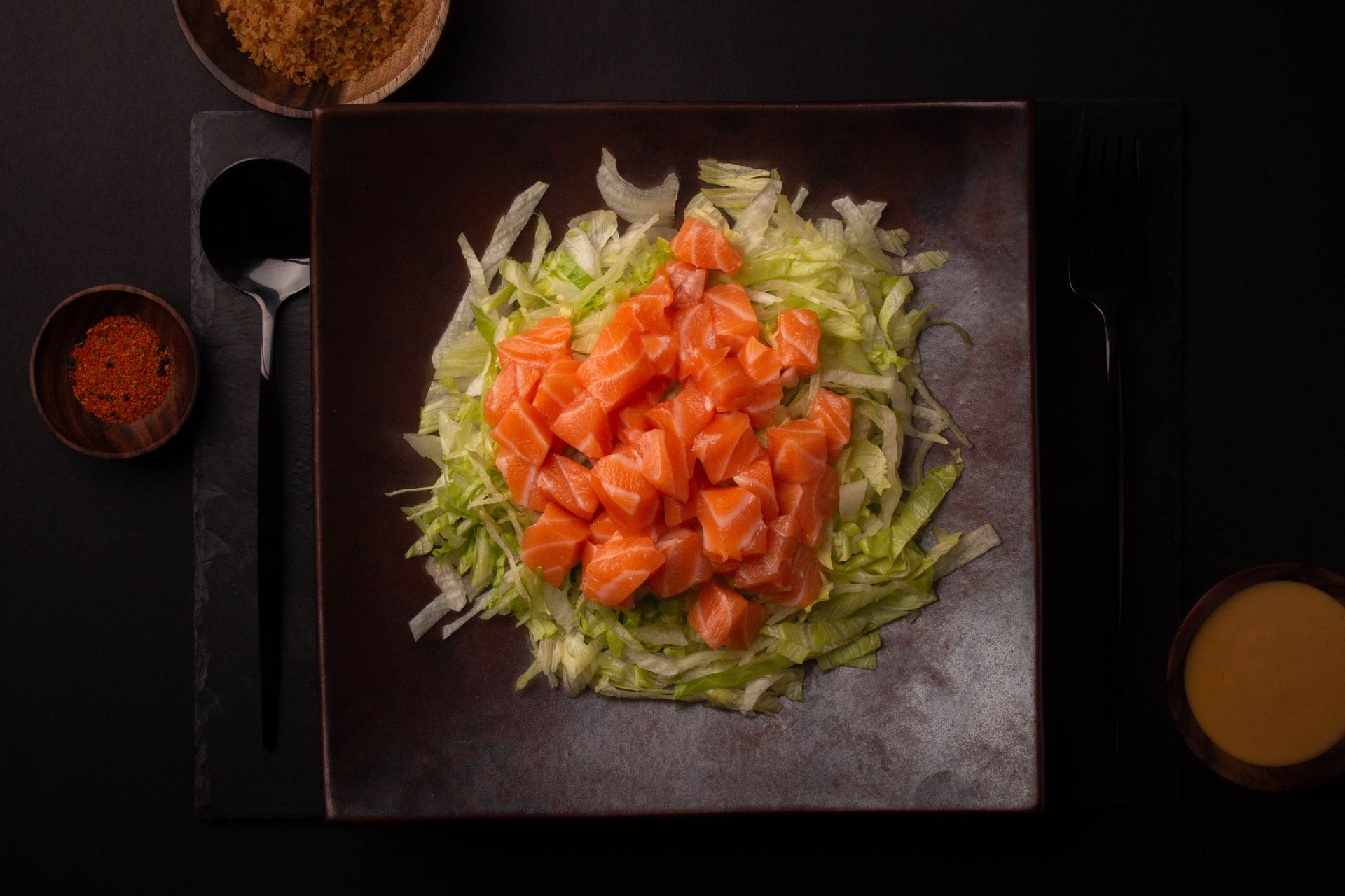 Sushi Restaurant | Finding Sushi | Salmon poke bowl with shredded lettuce, surrounded by sauce bowls and seasonings