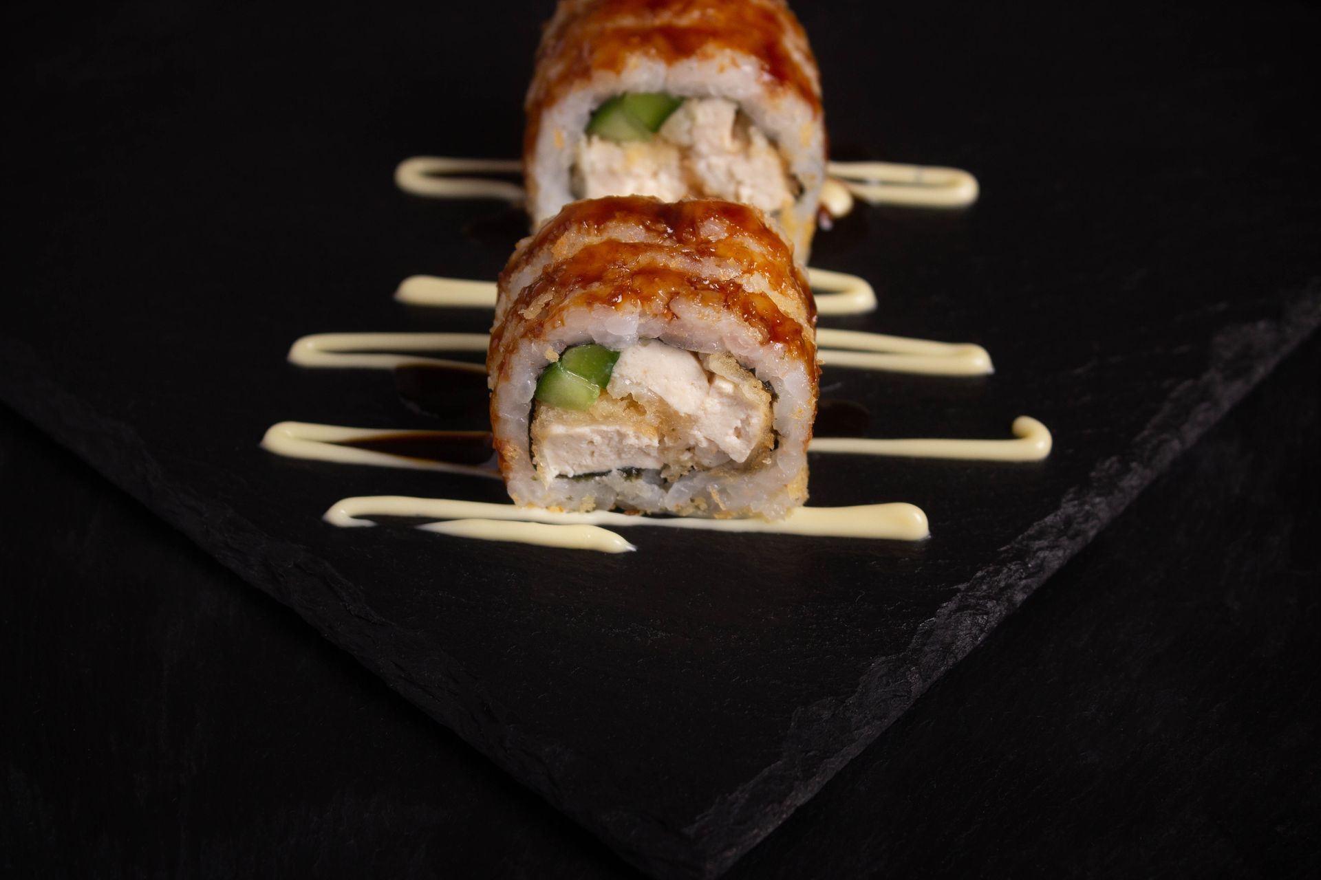 Sushi Restaurant | Finding Sushi | Sushi roll sliced on black slate, garnished with bamboo skewers