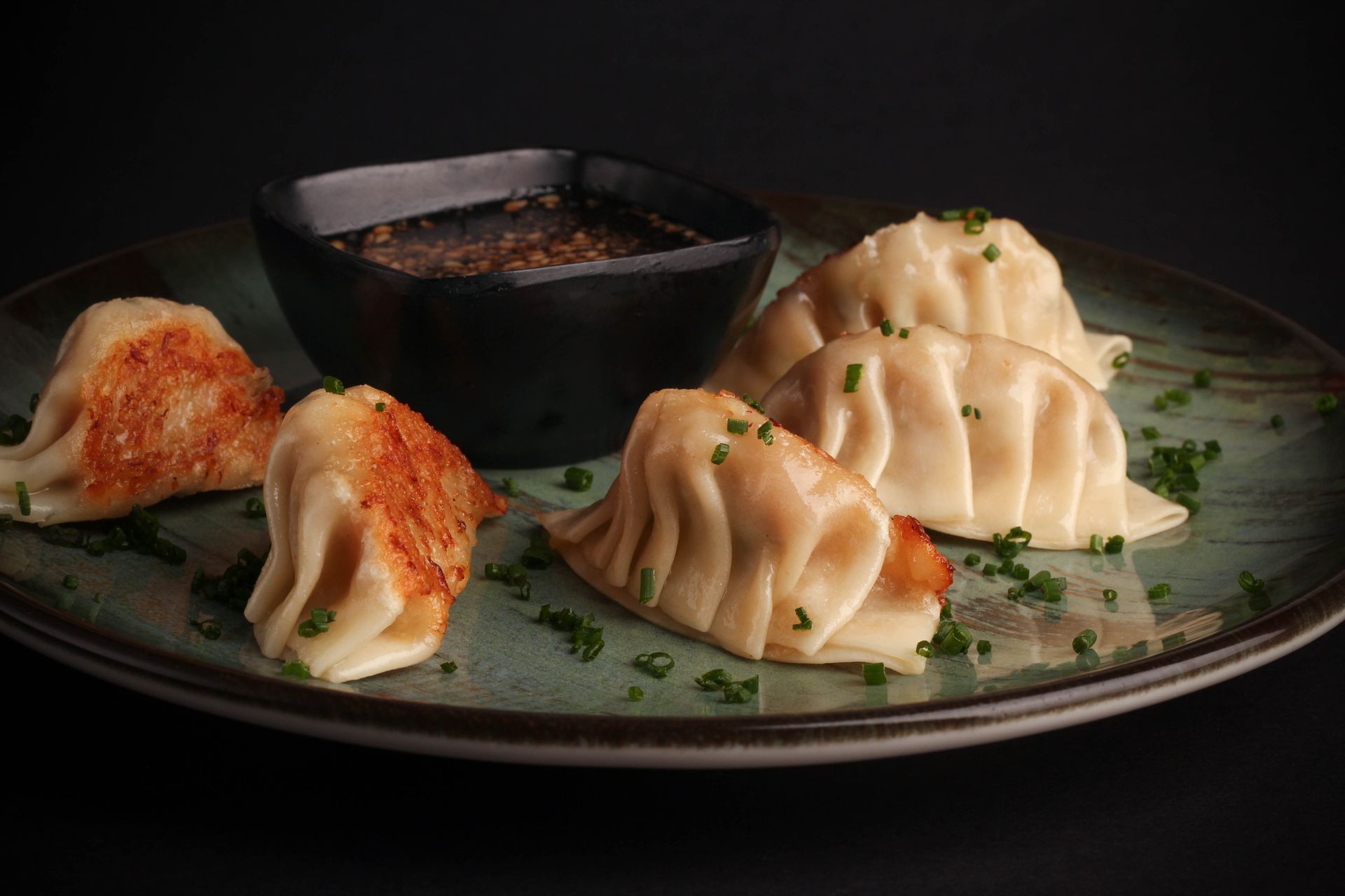 Sushi Restaurant | Finding Sushi | Dumplings on a plate with a bowl of dipping sauce, garnished with chopped herbs