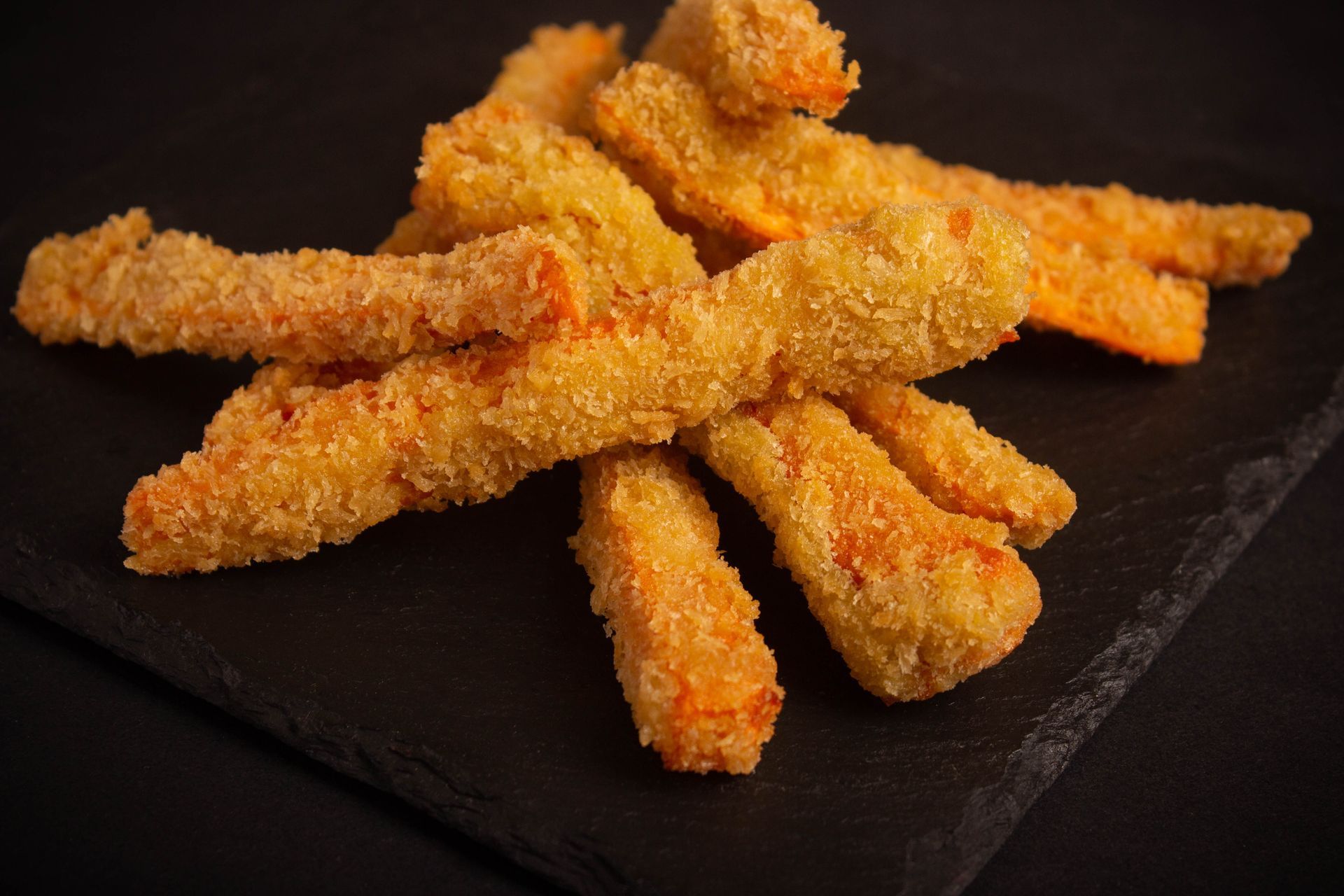 Sushi Restaurant | Finding Sushi | Crispy breaded fries stacked on a dark plate against a black background