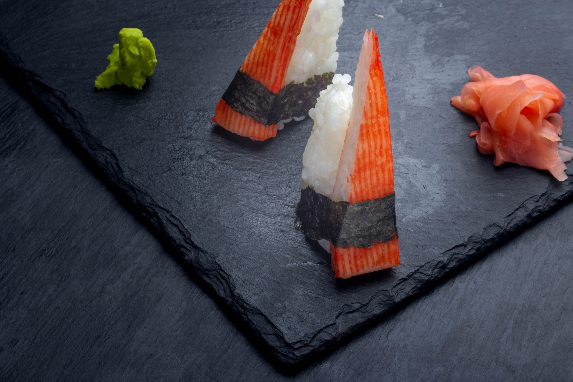 Sushi Restaurant | Finding Sushi | Sushi nigiri with crab sticks and wasabi on a black slate plate with pickled ginger