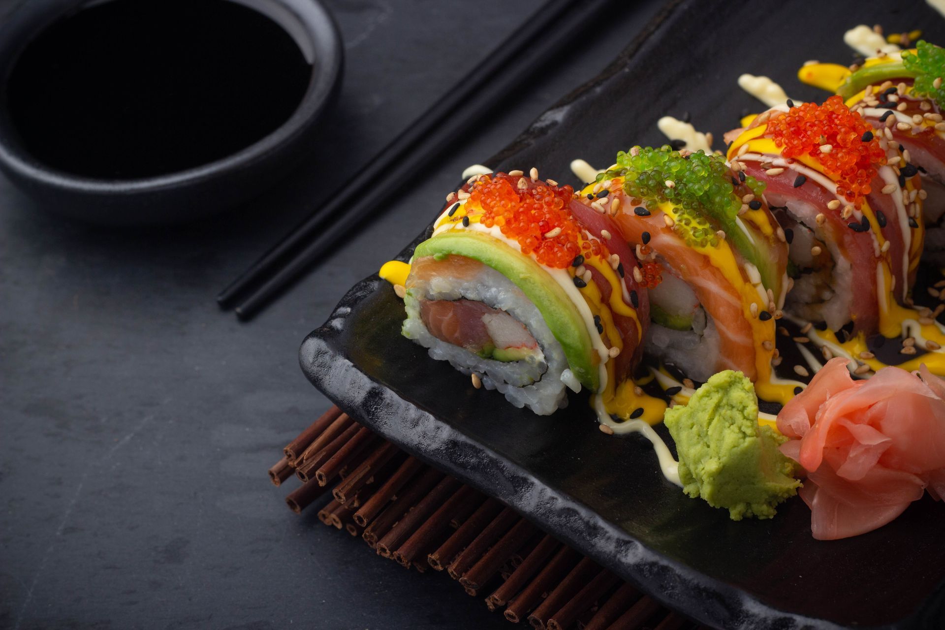Sushi Restaurant | Finding Sushi | Sushi rolls on a black platter with chopsticks, soy sauce, and pickled ginger,