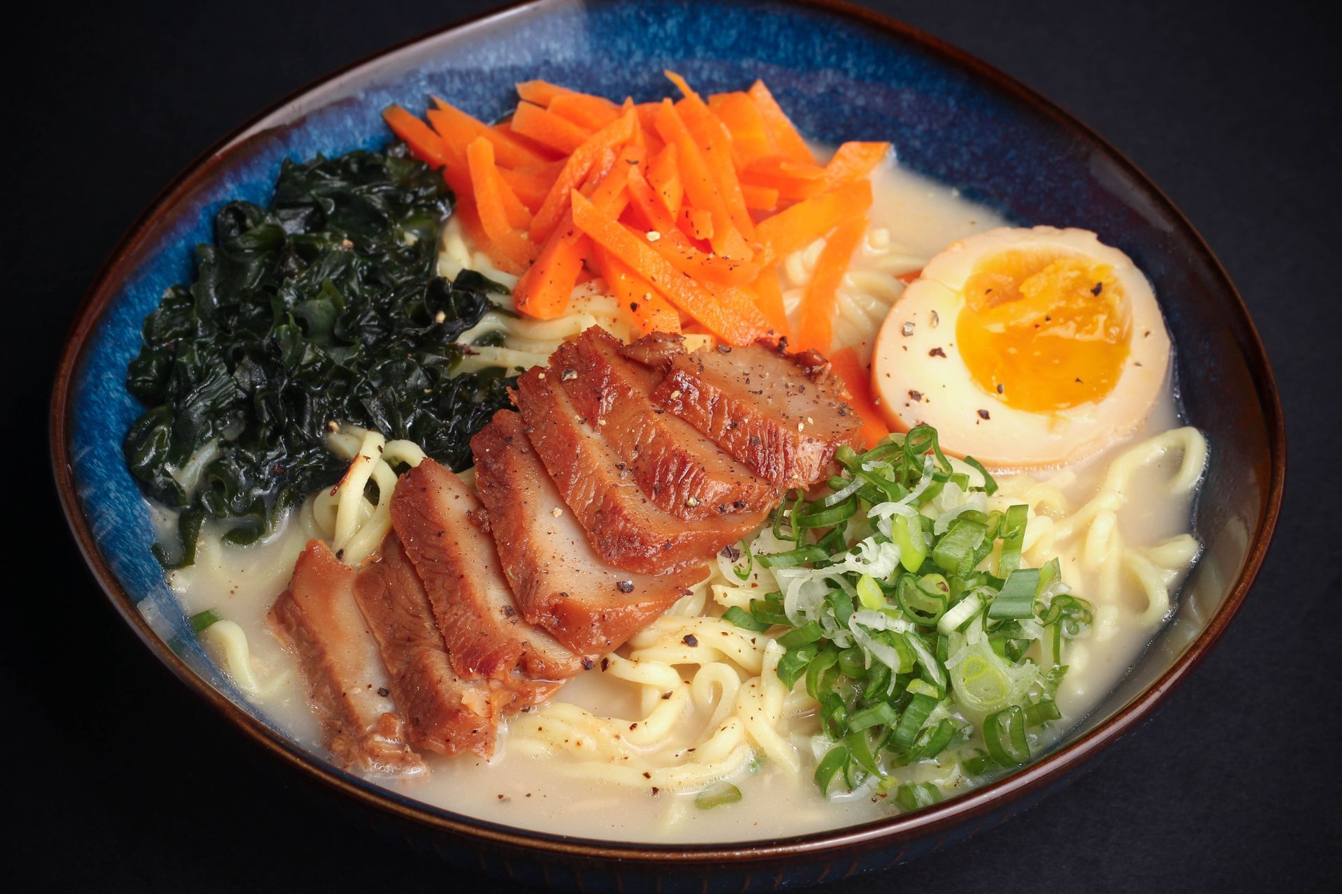 Sushi Restaurant | Finding Sushi | Bowl of ramen topped with sliced pork, soft egg, greens, seaweed, and shredded carrots