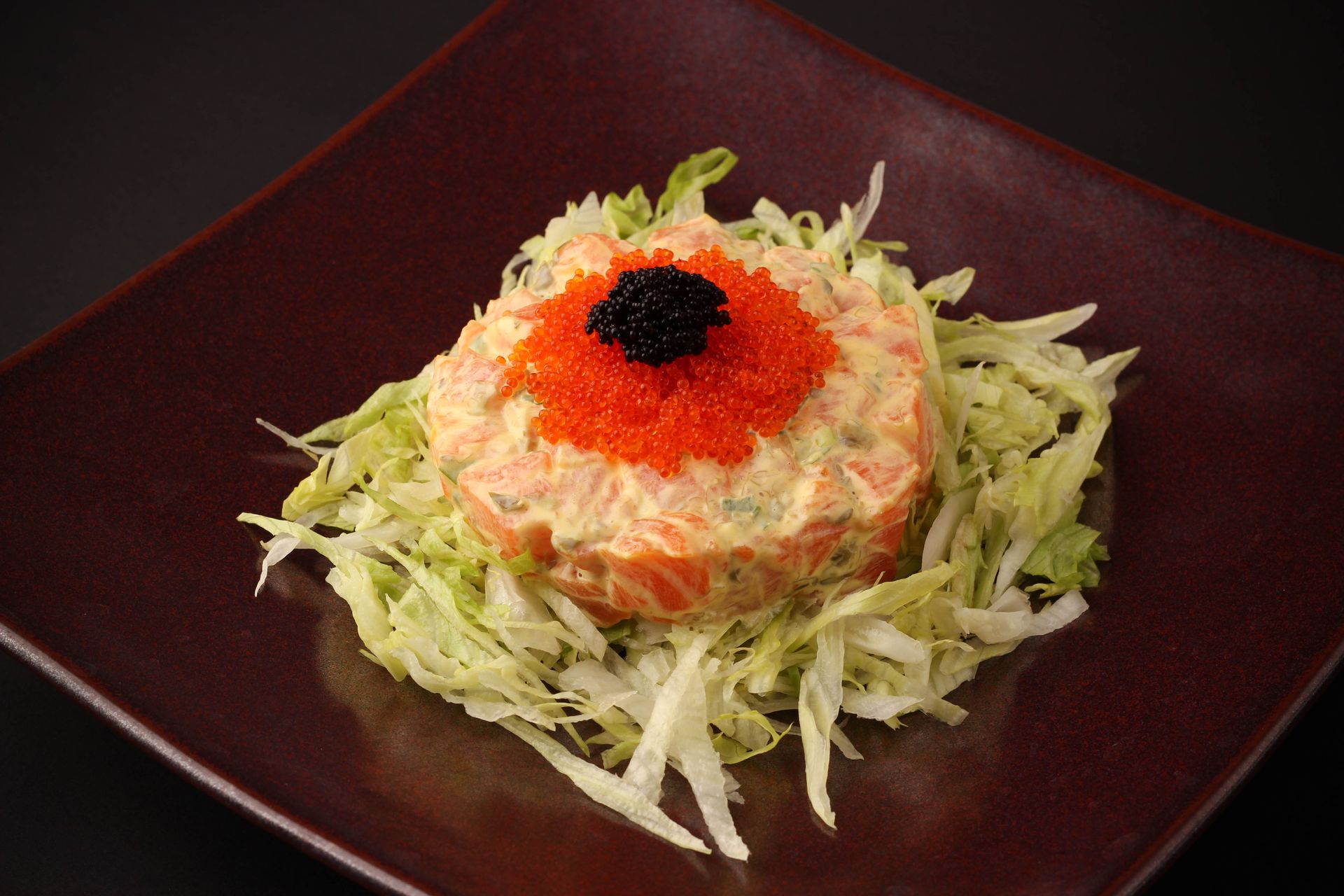 Sushi Restaurant | Finding Sushi | Shredded salad topped with orange garnish and black caviar on a dark red square plate