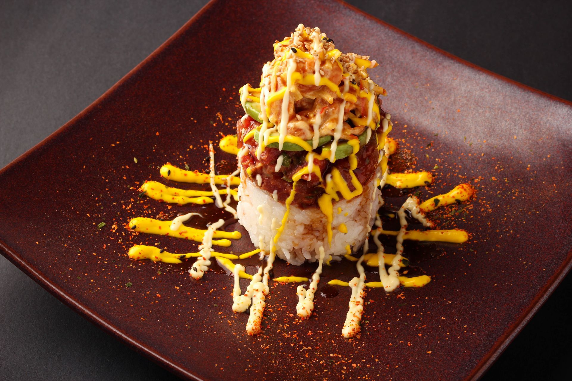 Sushi Restaurant | Finding Sushi | Gourmet sushi roll topped with sauce and crispy garnish on a dark square plate