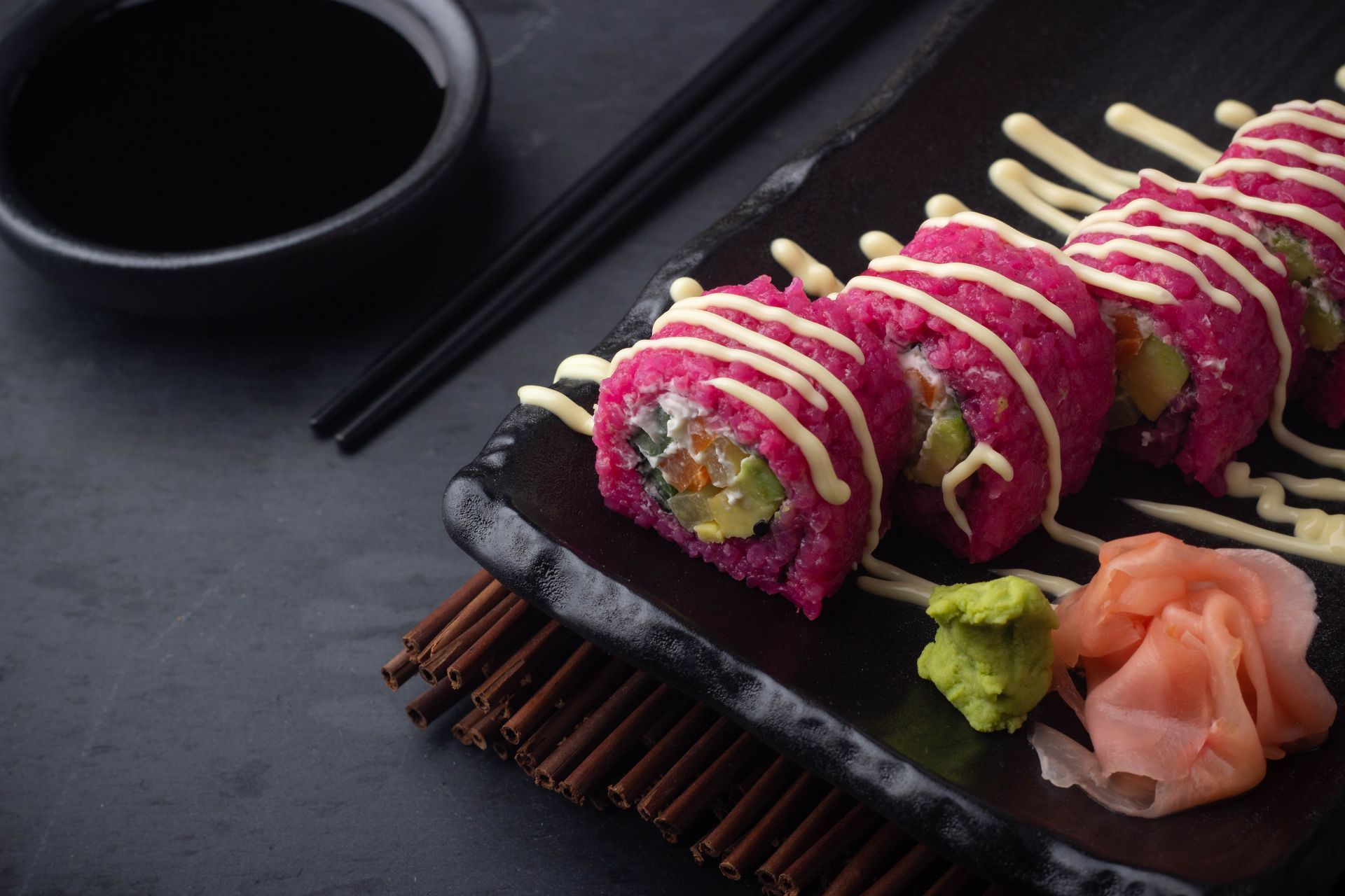 Sushi Restaurant | Finding Sushi | Pink sushi rolls on a black tray with chopsticks, wasabi, pickled ginger, and soy sauce
