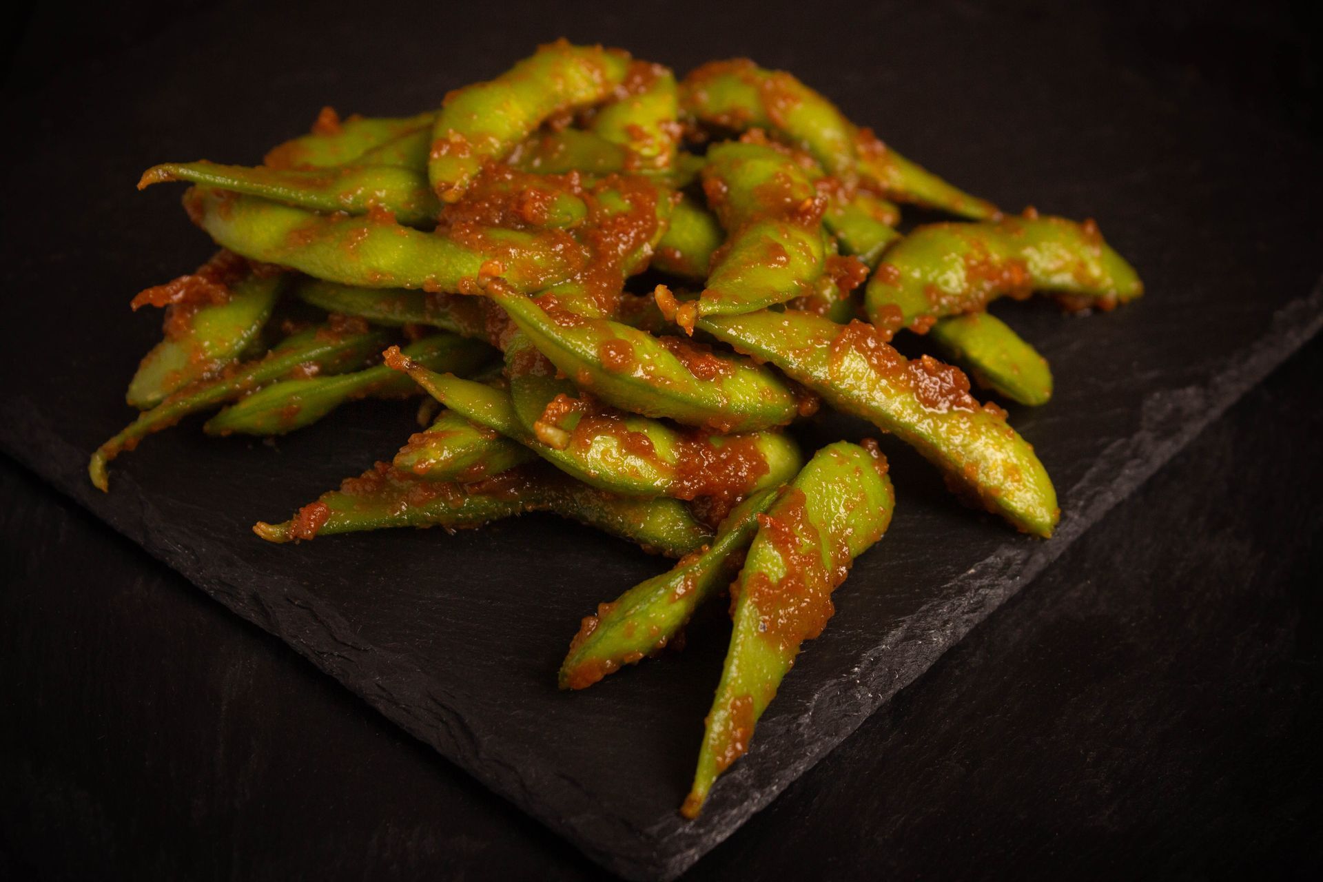 Sushi Restaurant | Finding Sushi | Spicy green edamame pods piled on a dark slate plate