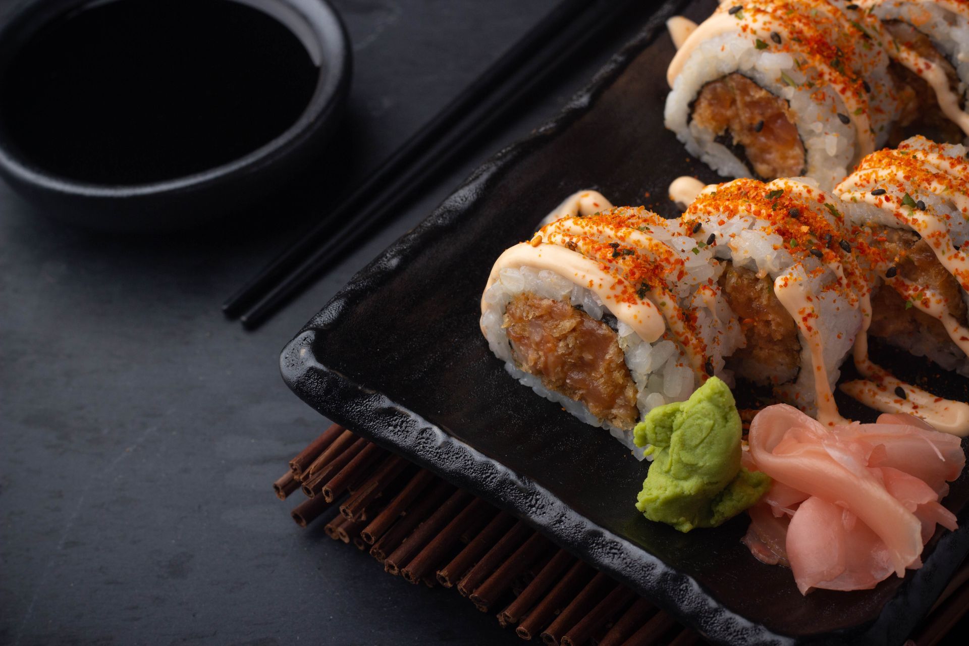 Sushi Restaurant | Finding Sushi | Sushi rolls on a black plate with soy sauce, chopsticks, pickled ginger