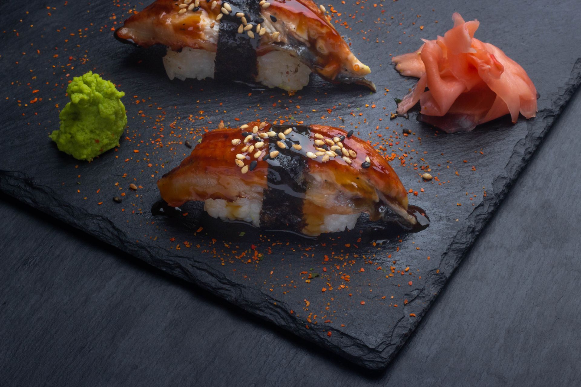 Sushi Restaurant | Finding Sushi | Glazed sushi rolls on a dark slate plate with wasabi and pickled ginger