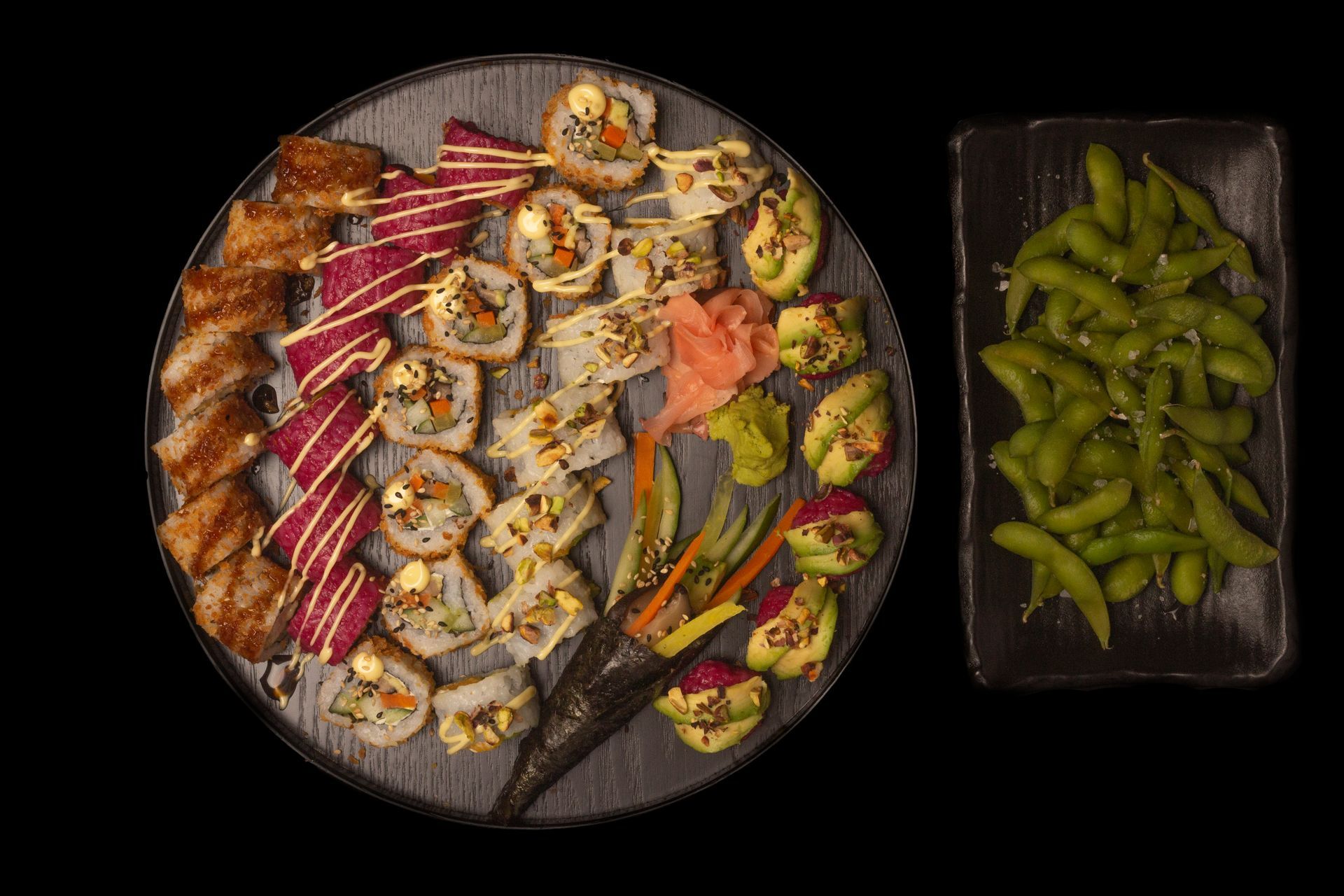 Sushi Restaurant | Finding Sushi | Overhead view of a sushi platter with rolls, nigiri, and edamame in a black tray