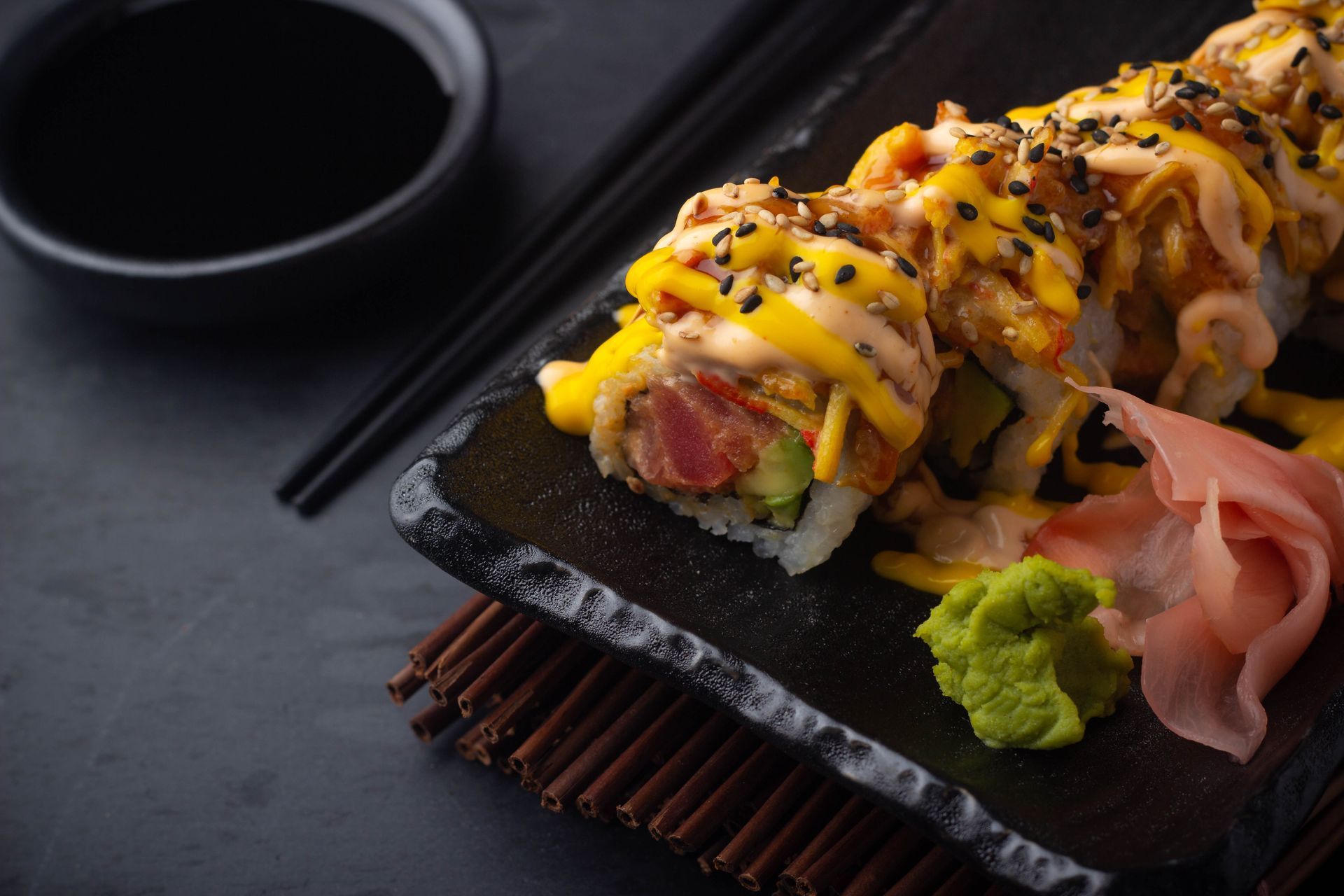 Sushi Restaurant | Finding Sushi | Sushi rolls with pickled ginger and wasabi on a dark table.