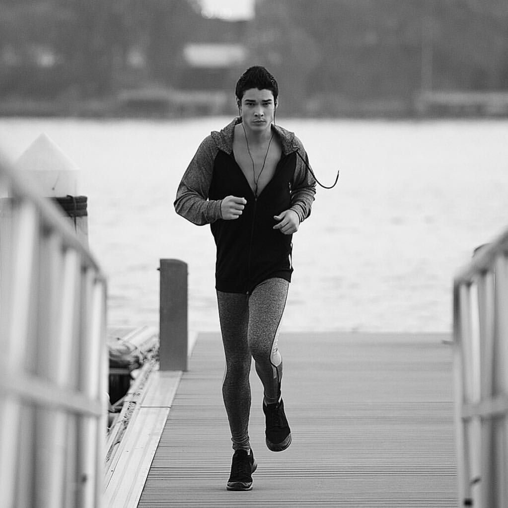 A black and white photo of a man running on a dock